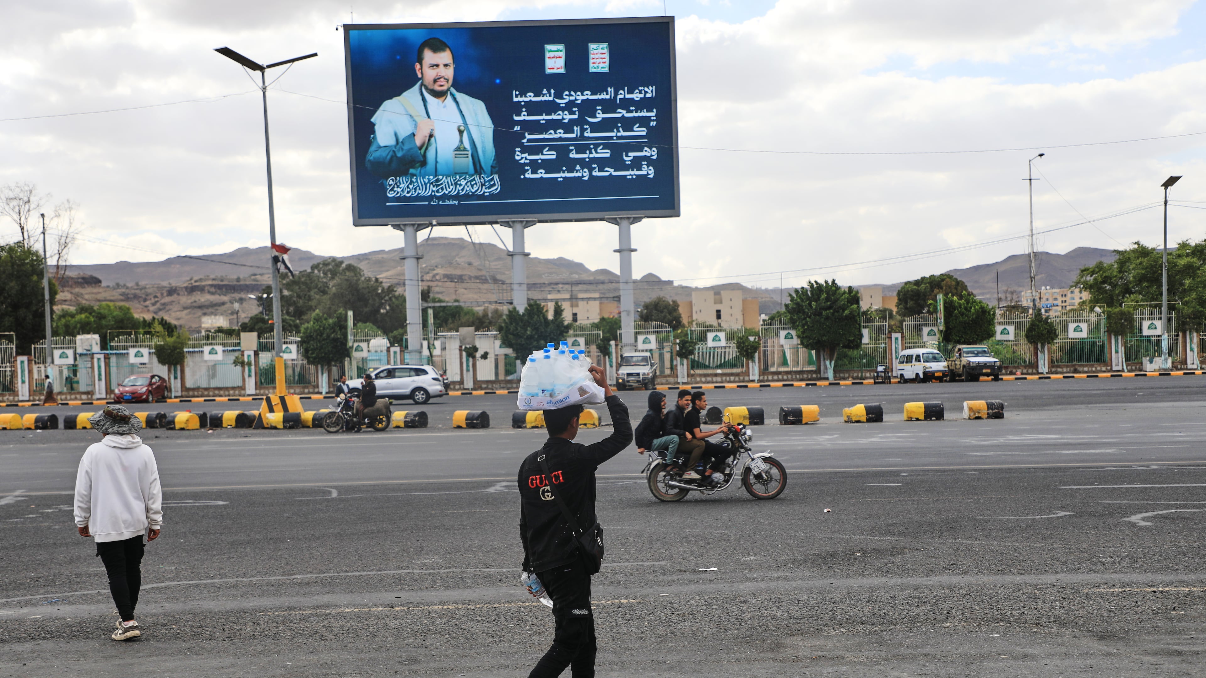 A vendor walks under a billboard showing Houthi leader Abdul Malik al-Houthi with a phrase that reads in Arabic: "The Saudi accusation against our people deserves to be described as the lie of the century" in Sanaa, Yemen, Monday, Oct. 5, 2026. (AP Photo/Osamah Abdulrahman)