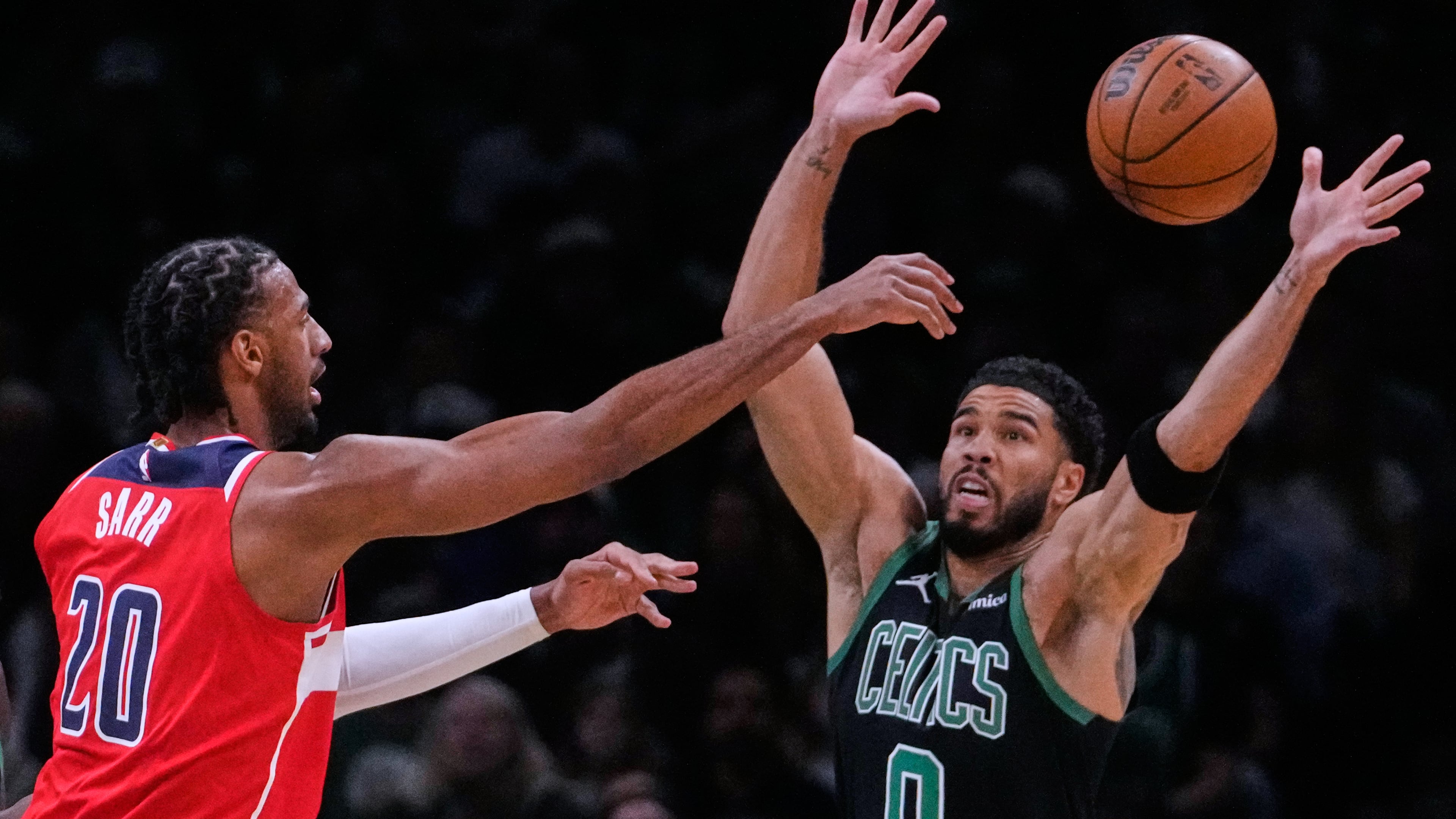 Boston Celtics forward Jayson Tatum (0) reaches up to block a pass by Washington Wizards center Alex Sarr (20) during the first half of an NBA basketball game, Saturday, March 14, 2026, in Boston. (AP Photo/Charles Krupa)