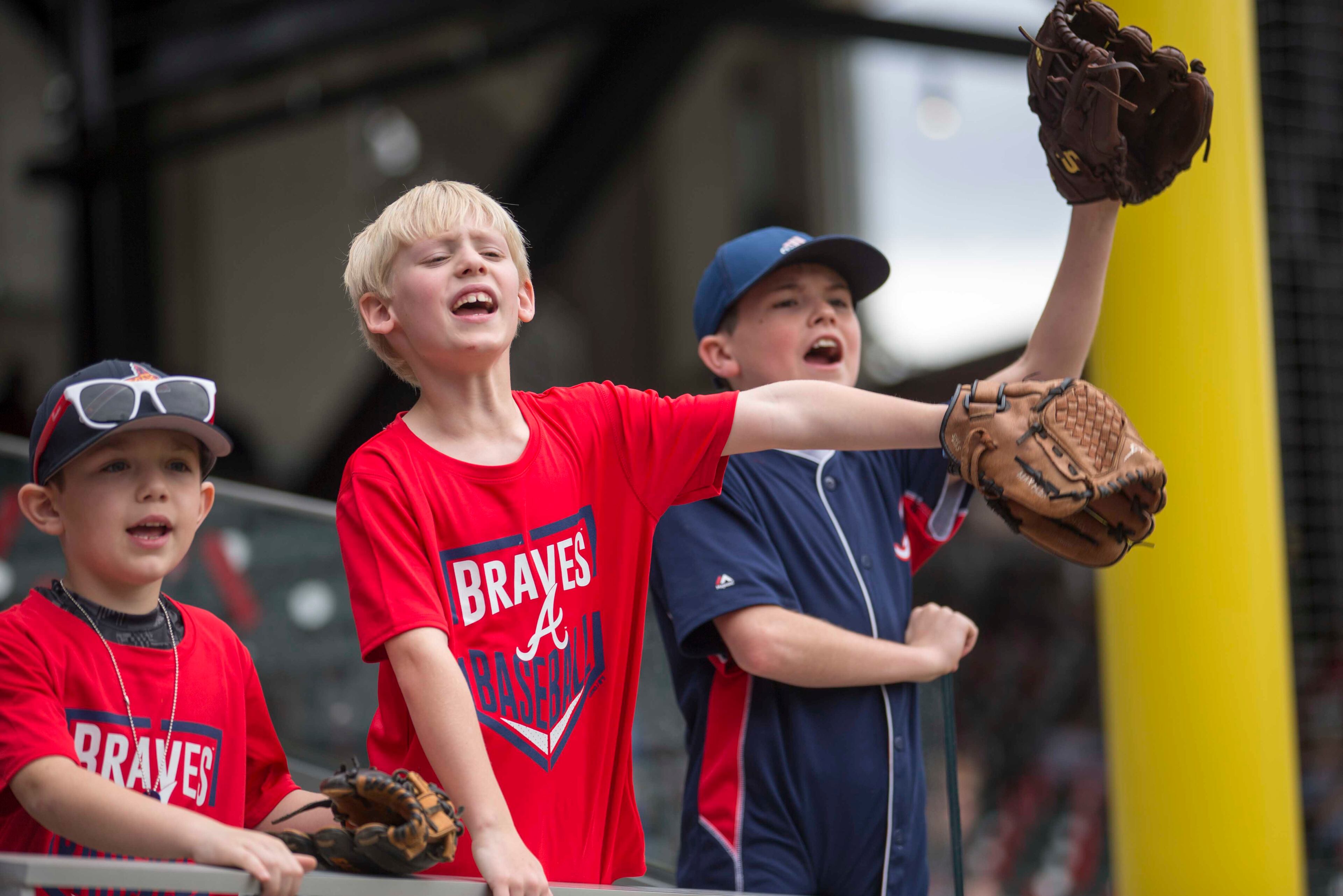 03/29/2018 -- Atlanta, GA - Braxton Butler, from left, Easton Moody, center, and Walker Bruins, right, try to get the attention of a Philadelphia Phillies player during practice at SunTrust Park before the Atlanta Braves season opener game, Thursday, March 29, 2018. ALYSSA POINTER/ALYSSA.POINTER@AJC.COM