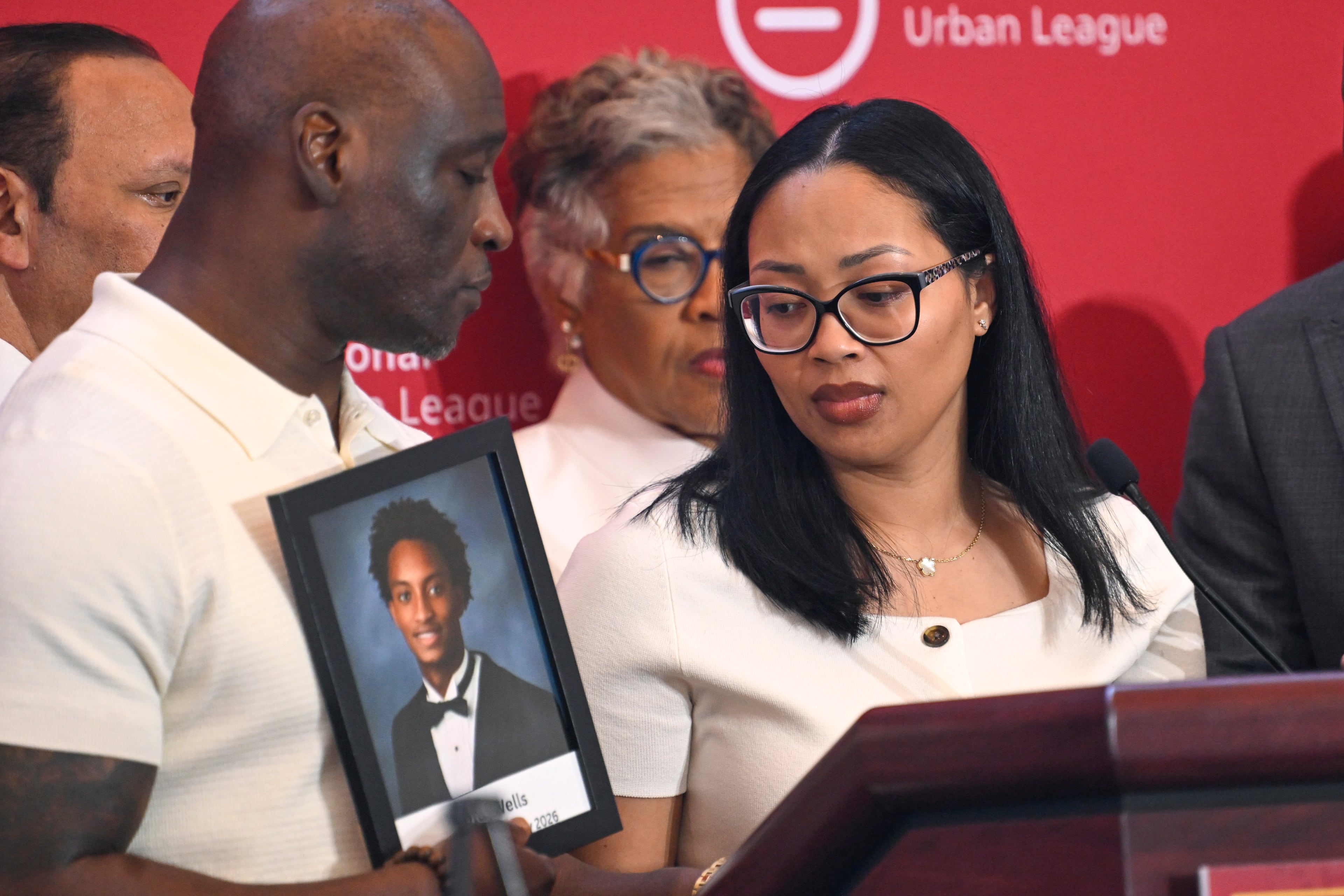 Christine Wonsley looks at a photo of her deceased son, Nolan Wells, as husband Elmore Wonsley, left, stands at her side as they appear at the National Urban League's annual conference, Thursday, July 30, 2026, in Nashville, Tenn. (John Amis/AP)