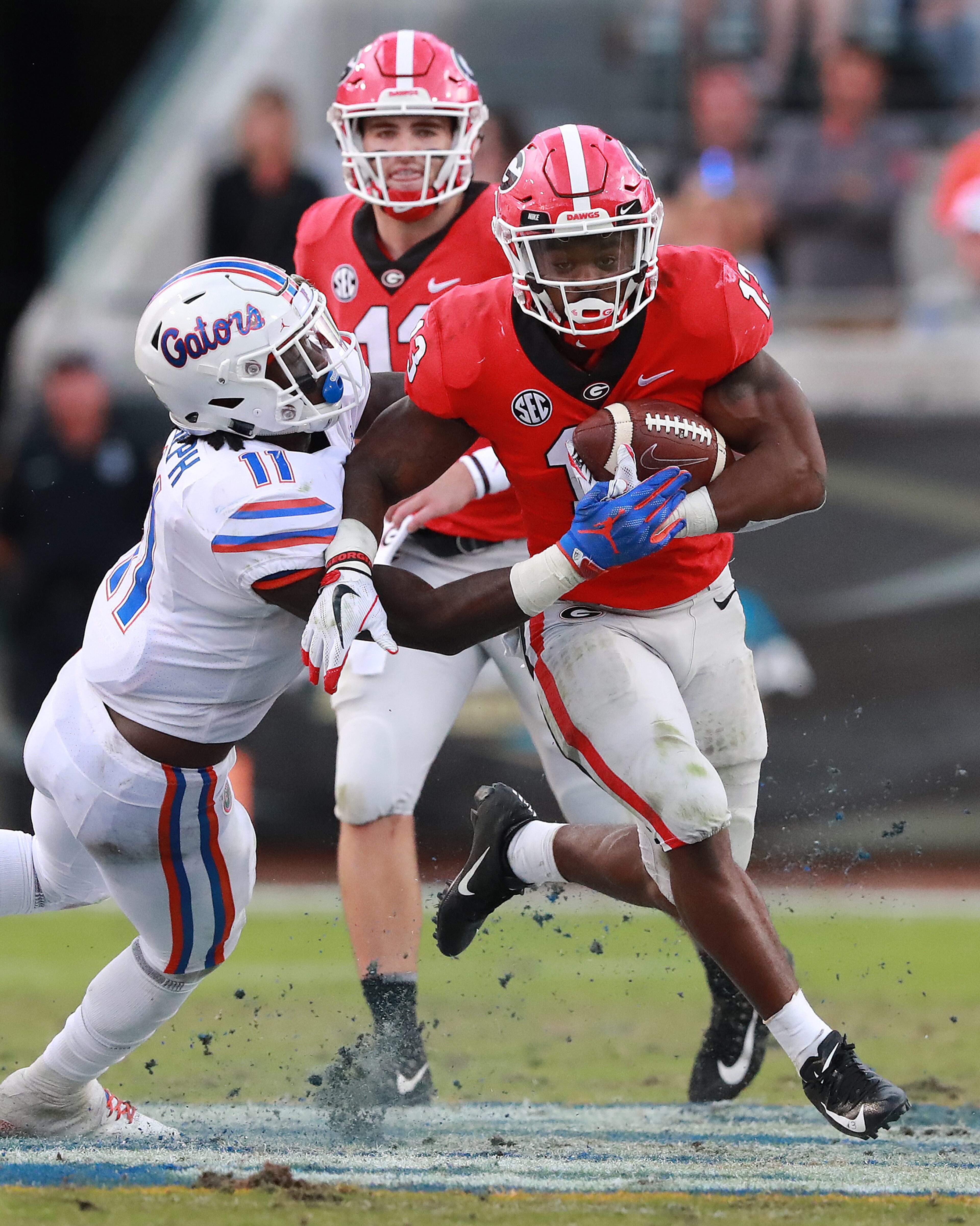 October 27, 2018 Jacksonville: Georgia quarterback Jake Fromm hands off to tailback Elijah Holyfield for yardage against Florida linebacker Vosean Joseph during the second half in the Georgia-Florida NCAA college football game on Saturday, Oct 27, 2018, in Jacksonville. Curtis Compton/ccompton@ajc.com
