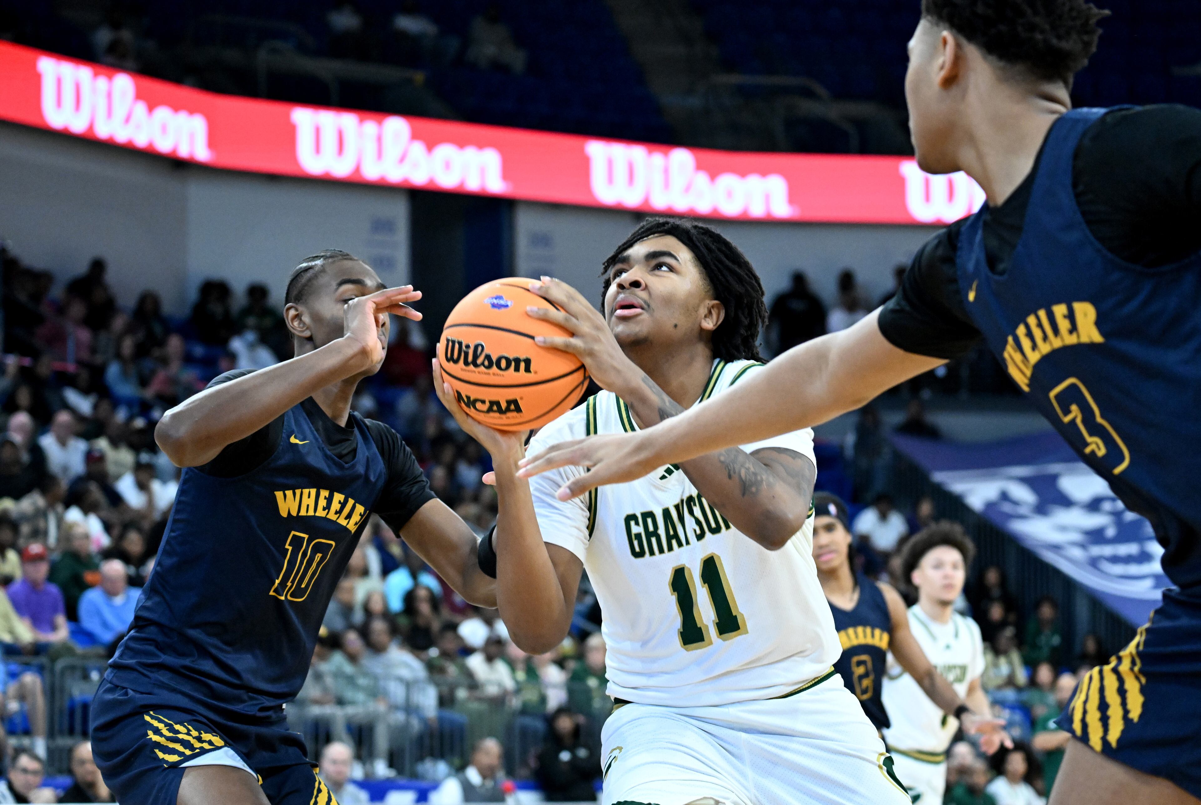 Grayson's Amir Taylor (11) drives between Wheeler's Tylis Jordan (10) and Wheeler's Colben Landrew (3) during the first half of the GHSA Class 6A Boys State Basketball playoffs game at the Georgia State Convocation Center, Saturday, March 1, 2025, in Atlanta. Wheeler won 68-53 over Grayson. (Hyosub Shin / AJC)