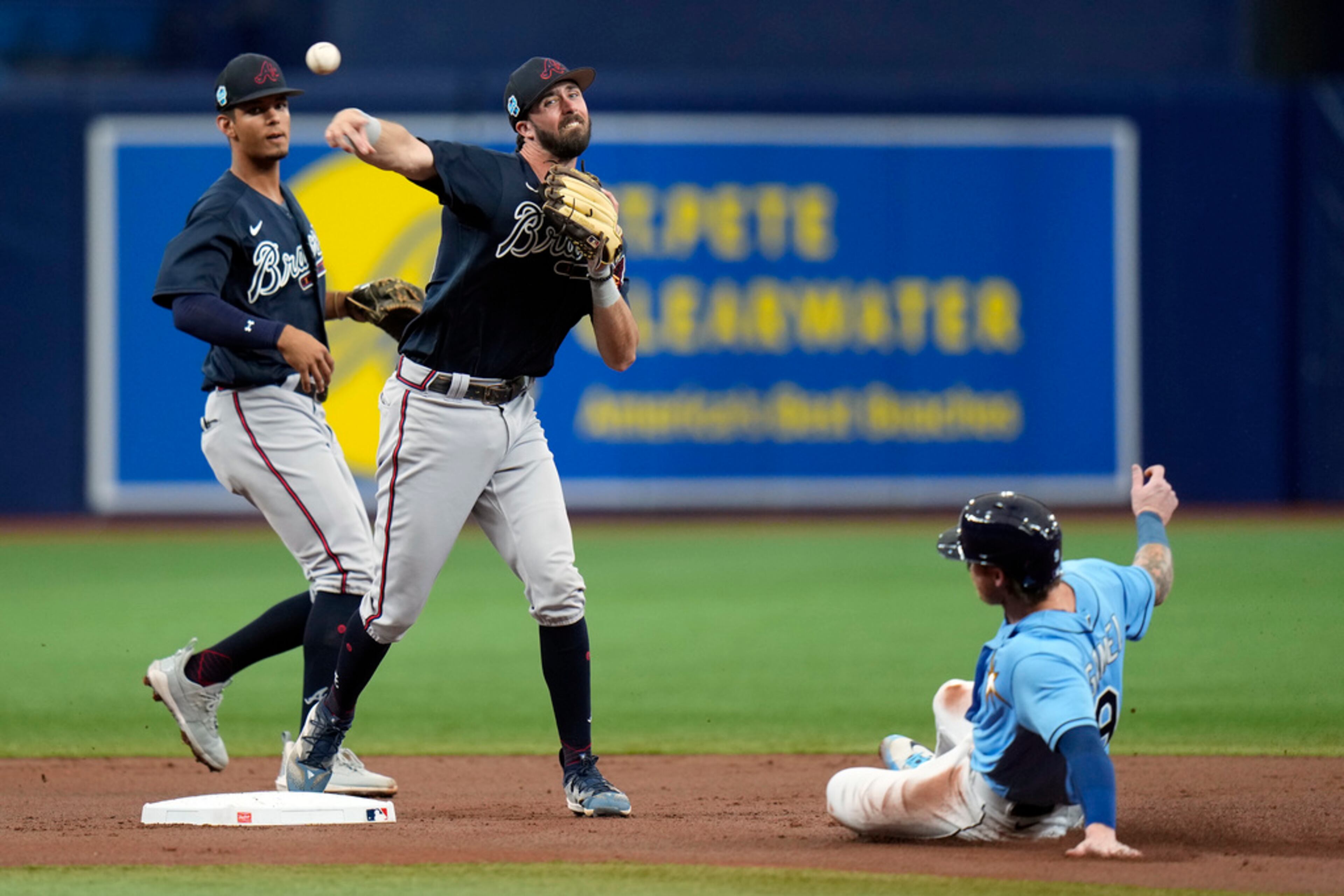 Atlanta Braves second baseman Braden Shewmake, center, forces Tampa Bay Rays' Ben Gamel, right, at second base and relays the throw to first in time to turn a double play on Manuel Margot during the first inning of a spring training baseball game Friday, March 10, 2023, in St. Petersburg, Fla. Looking on is Braves' Vaughn Grissom, left. (AP Photo/Chris O'Meara)