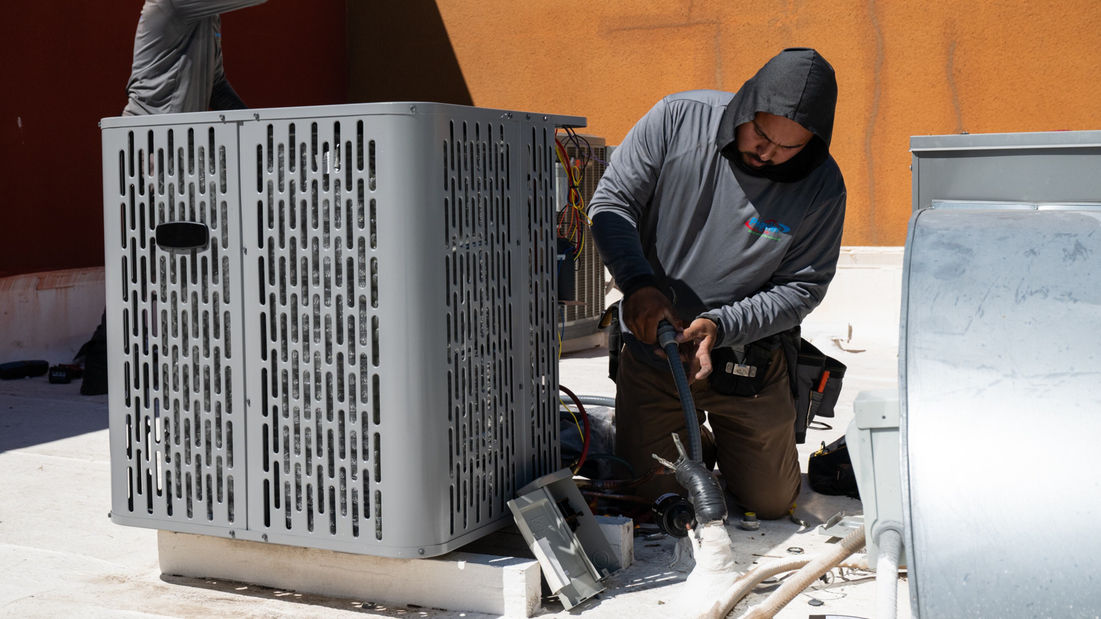 FILE - Sonel Telemaque, left, wipes sweat from his brow while installing a new air conditioning unit alongside Brian Hermosillo during record-breaking heat, March 19, 2026, in Tempe, Ariz. (AP Photo/Caitlin O'Hara, File)