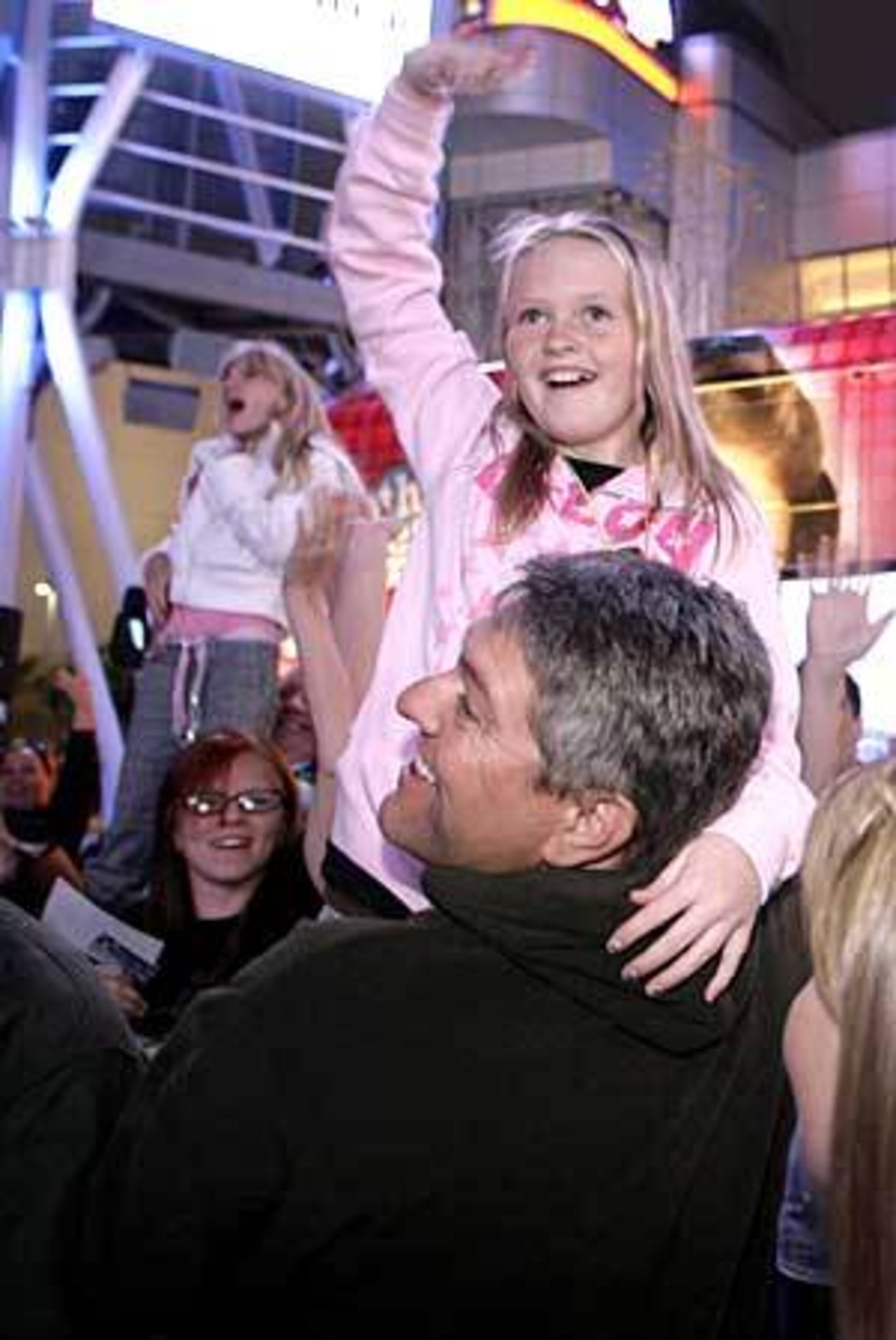 Paige Johnson, 10, of Nipomo, Calif., is held up by her dad, Tim, amid fans at the Ultimate Miley Party Bus Tour 2007.