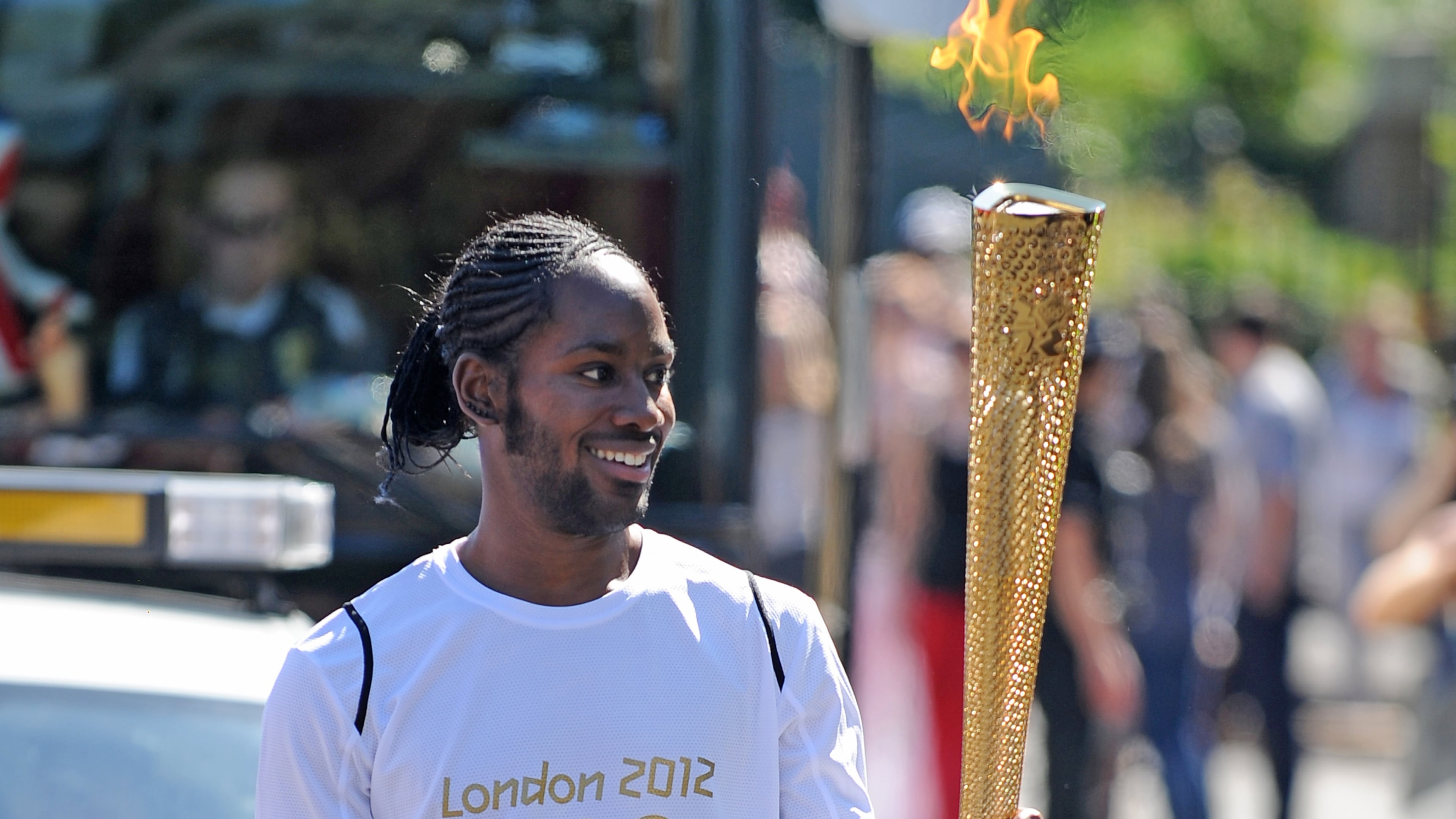 Torchbearer Jason Arday carries the Olympic Flame on the Torch Relay leg between Sutton and Merton, in London, July 23, 2012. (Joe Giddens/LOCOG/PA via AP)