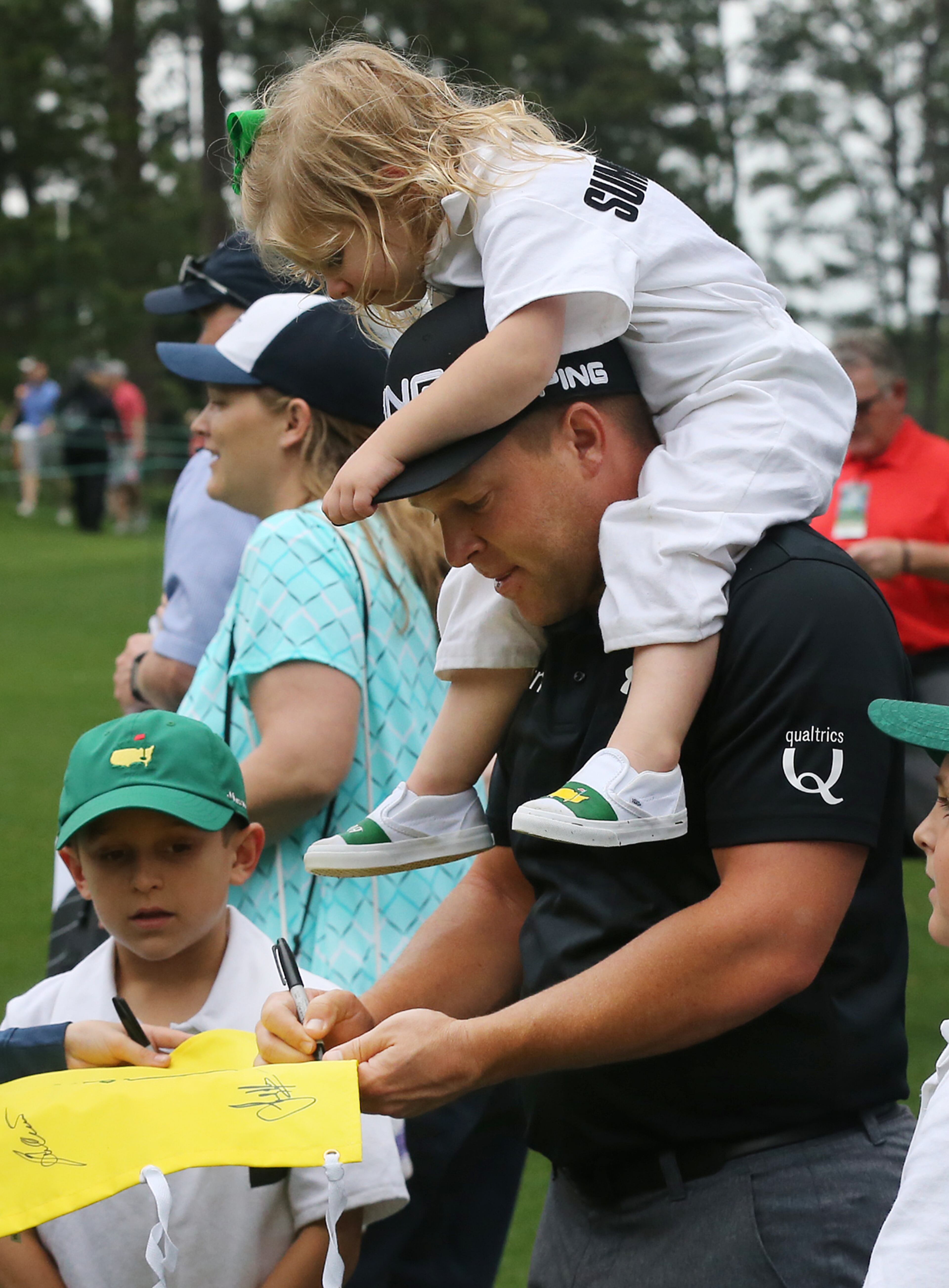 April 5, 2017, Augusta: Daniel Summerhays pauses to sign some authographs with his daughter Lydia on his shoulders after play was halted and the course closed for the day due to weather during the Masters Par 3 contest at Augusta National Golf Club on Wednesday, April 5, 2017, in Augusta. Curtis Compton/ccompton@ajc.com