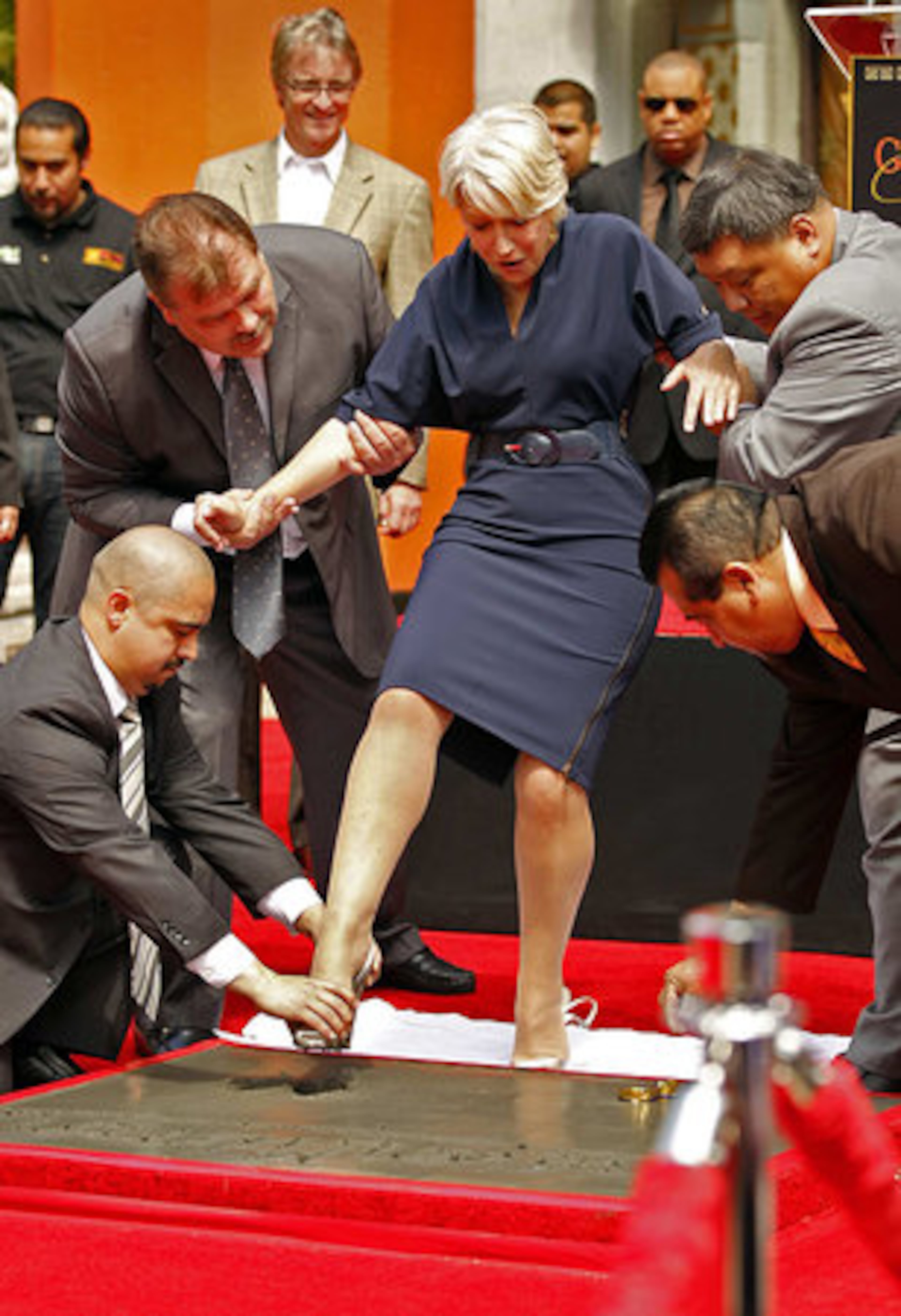 Helen Mirren gets some help while stepping into the wet cement.