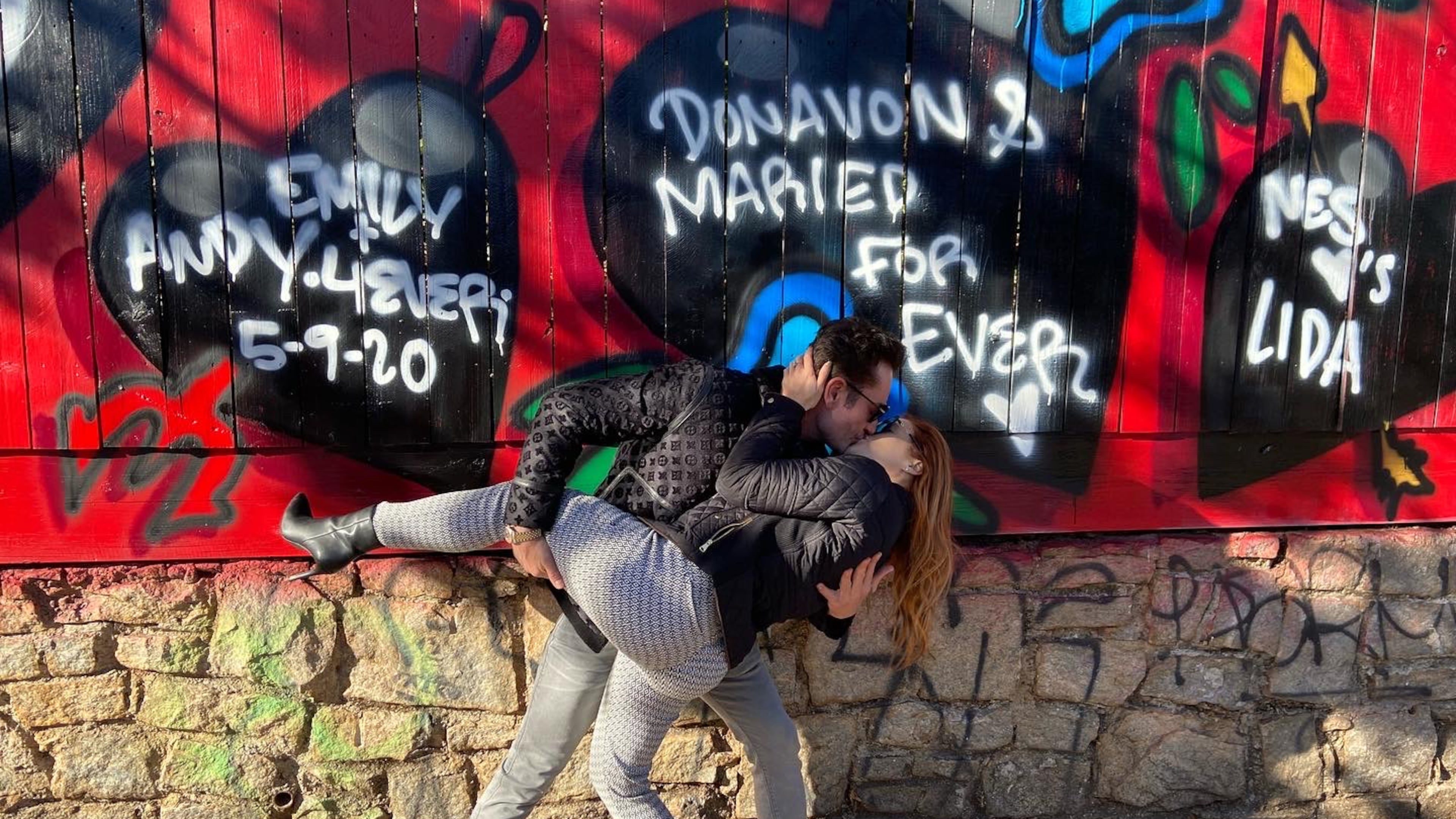 The annual Valentine's Day mural in Little Five Points gives individuals, families or organizations the opportunity to include a message to a loved one. A couple kisses in front of their heart painted behind Savage Pizza in Little Five Points. (Kelly Stocks photo)