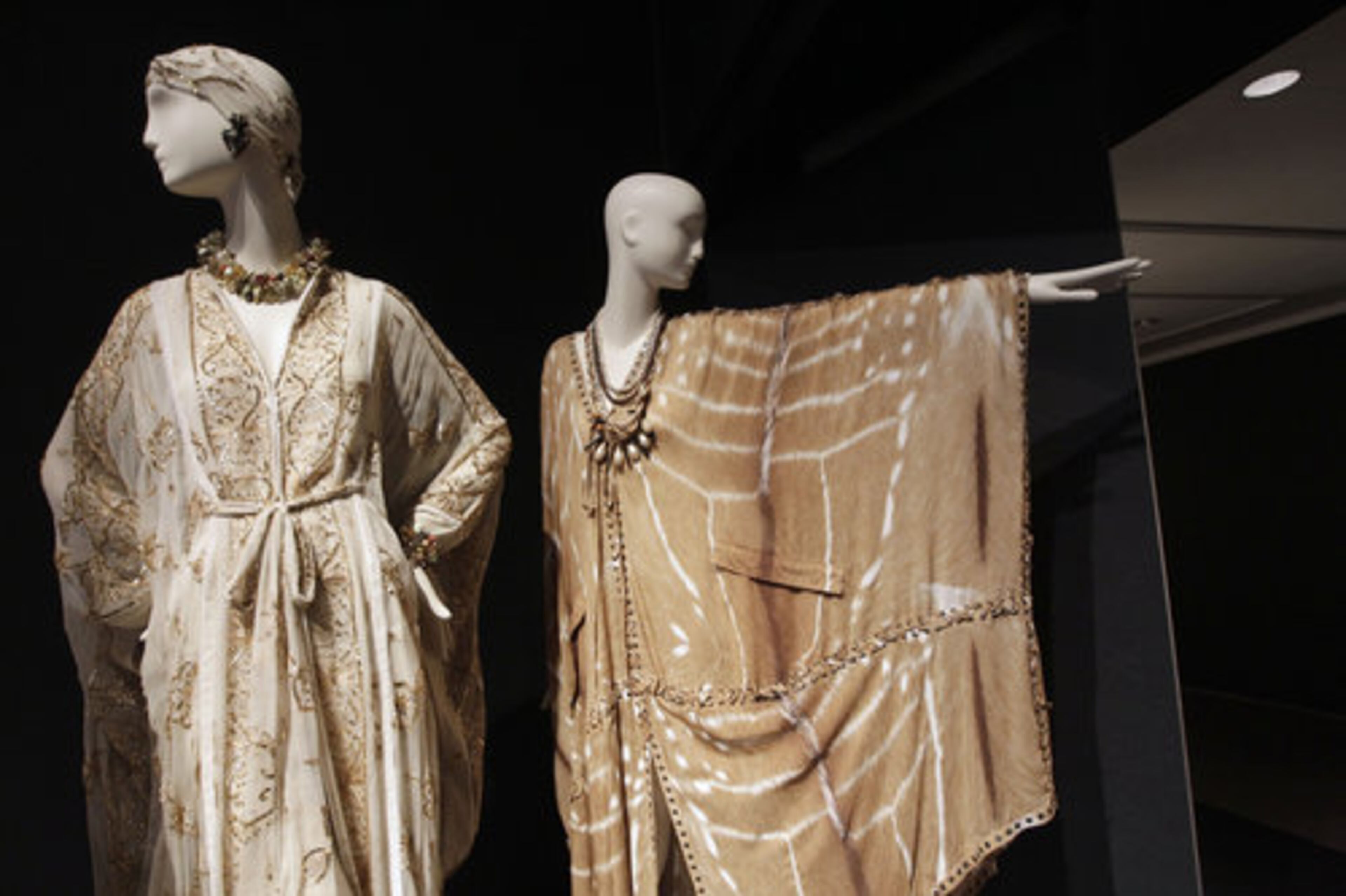 A Thea Porter Cream Chiffon Sequined and Embroidered Caftan with Matching Belt, left, and a Yves Saint Laurent Tan Safari Print Silk Cafta are displayed to preview the online and in-person auction.