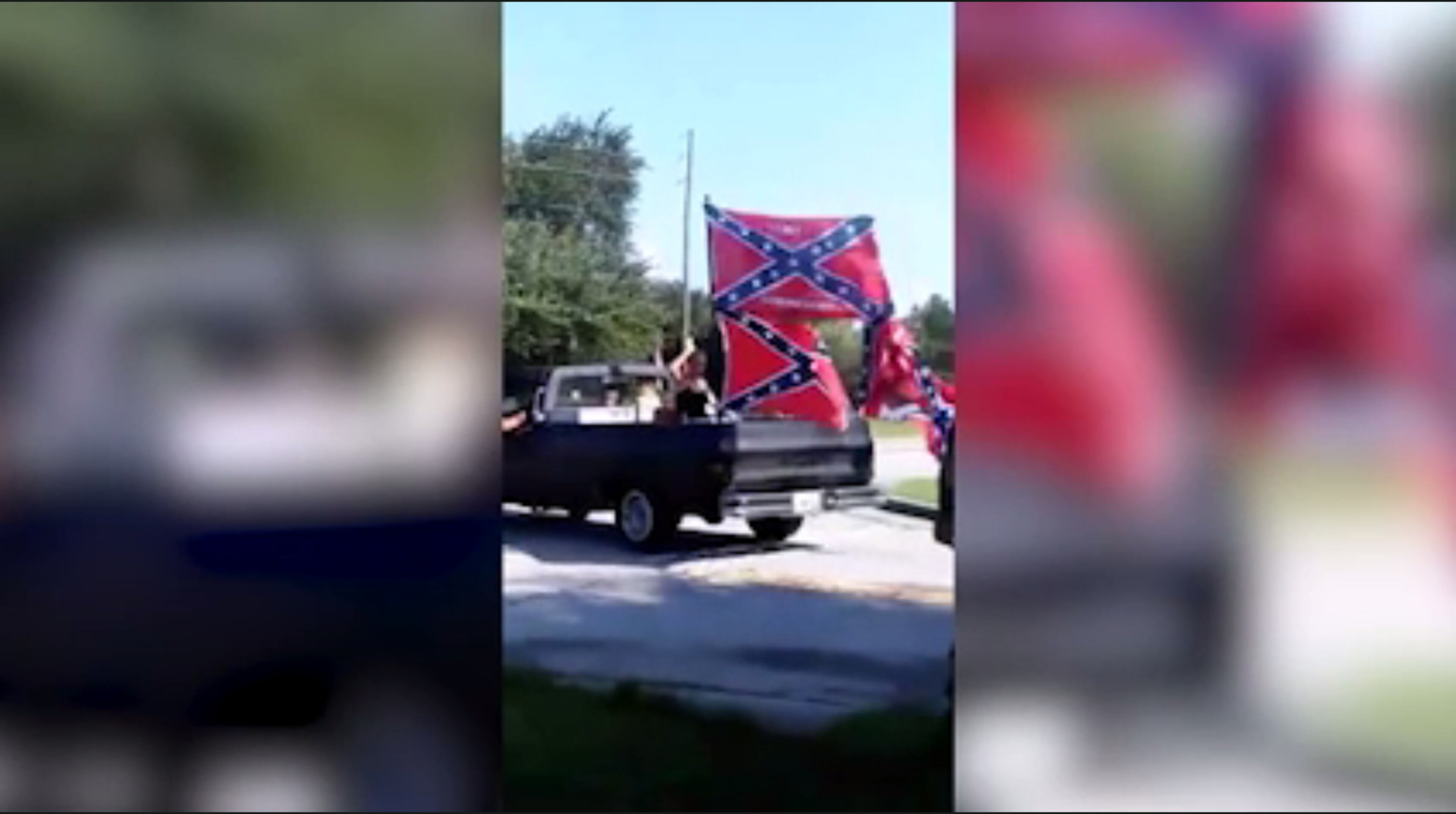 In this image from a phone video, trucks decked out with Confederate flags leave an area where the "Respect the Flag" group intimidated a black eight-year-old's birthday party next door. Police were on hand to see that the group was removed.