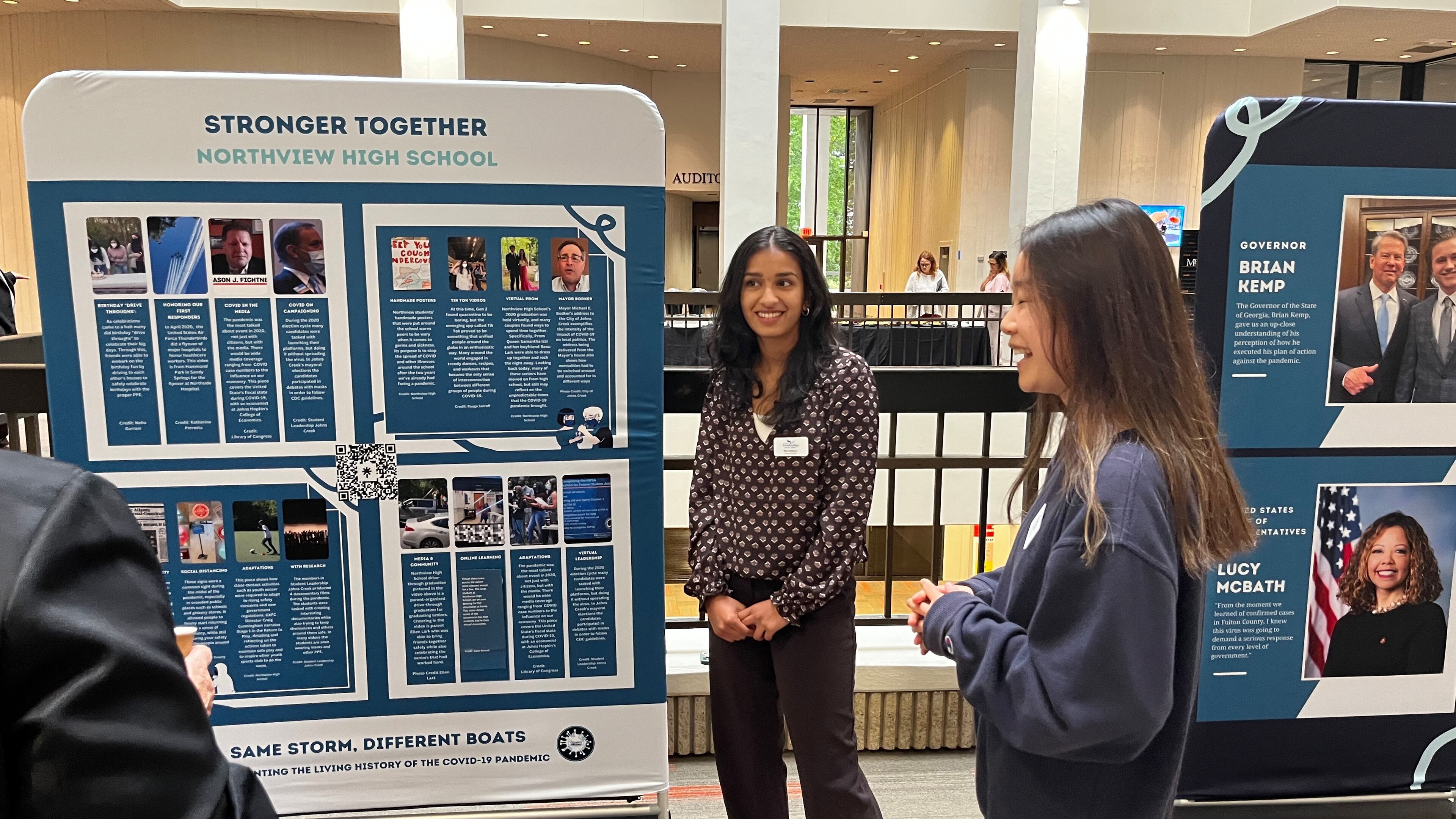 Northview High students Riya Havanur (center) and Irene Huang showcase the work they did with Student Leadership Johns Creek to document the pandemic's impact.