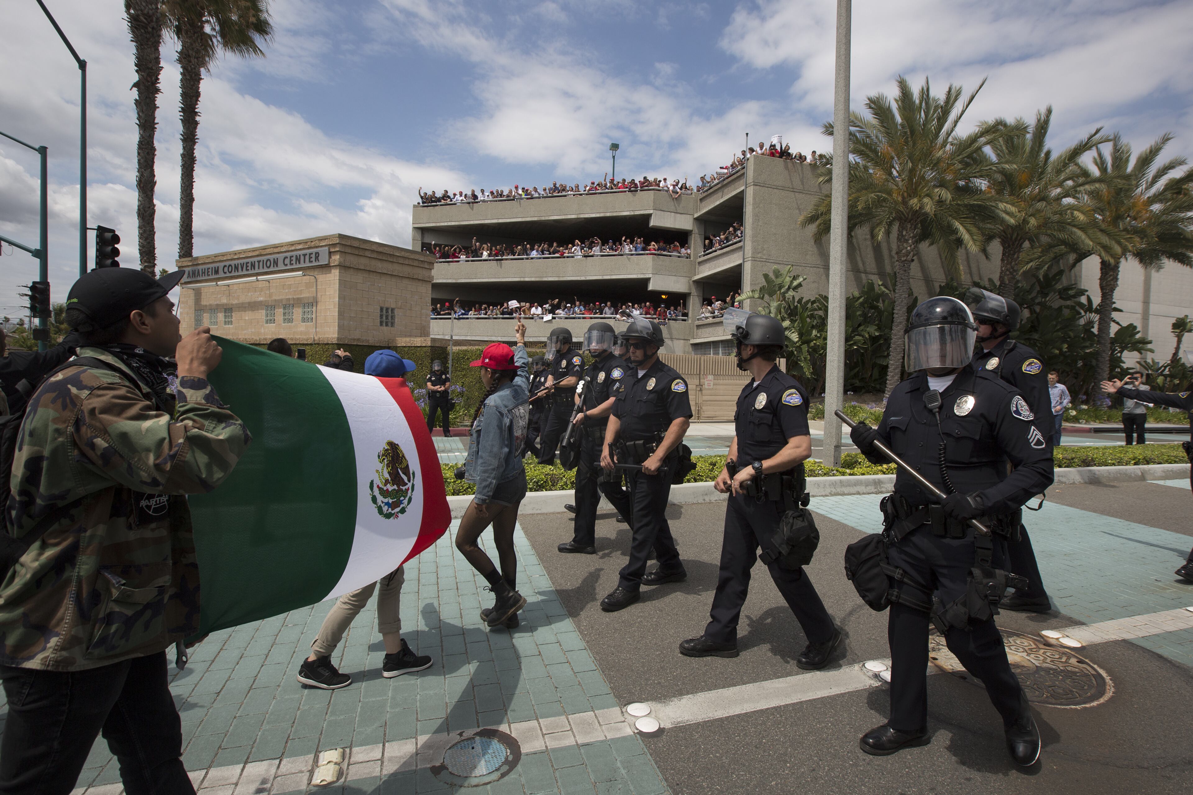 ANAHEIM, CA - MAY 25: Police force protesters down a street, away from Trump supporters jeering from a parking structure, near a campaign rally by presumptive GOP presidential candidate Donald Trump at the Anaheim Convention Center on May 25, 2016 in Anaheim, California. Previous visits by the candidate to Orange County have sparked in protests that resulted in some arrests. The presidential candidates are campaigning in Southern California for the June 7 California primary. (Photo by David McNew/Getty Images)