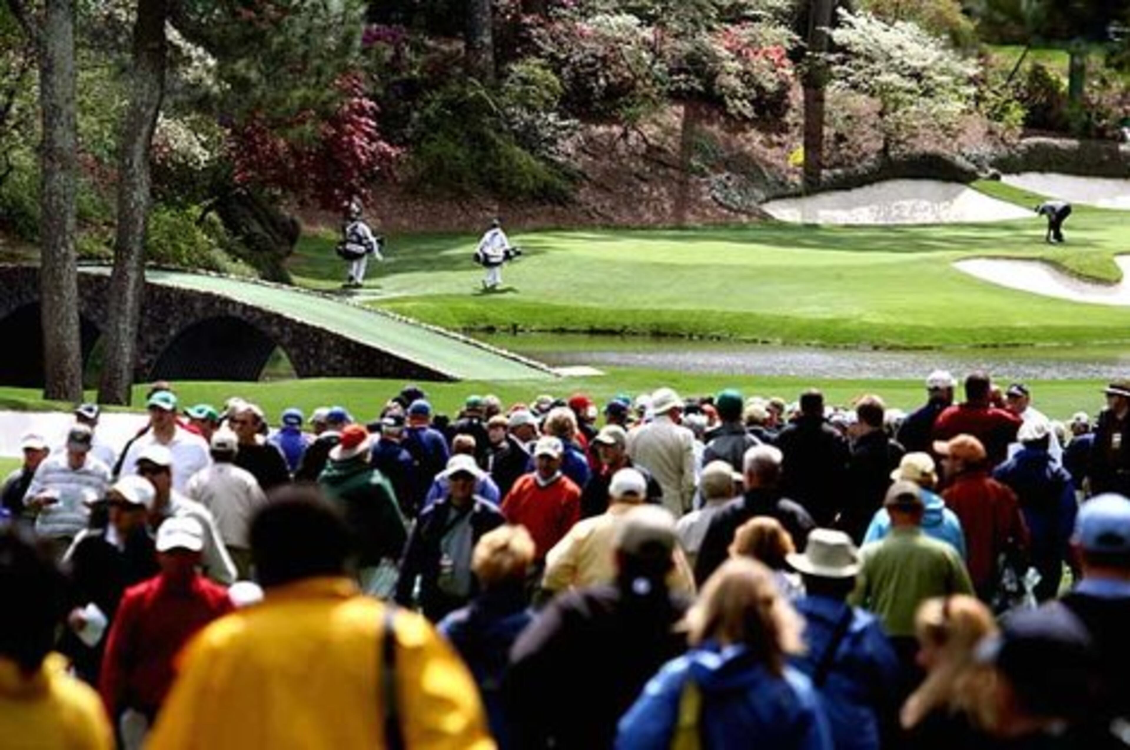 A crowd watches golfers approaching Amen Corner during the first day of practice rounds.