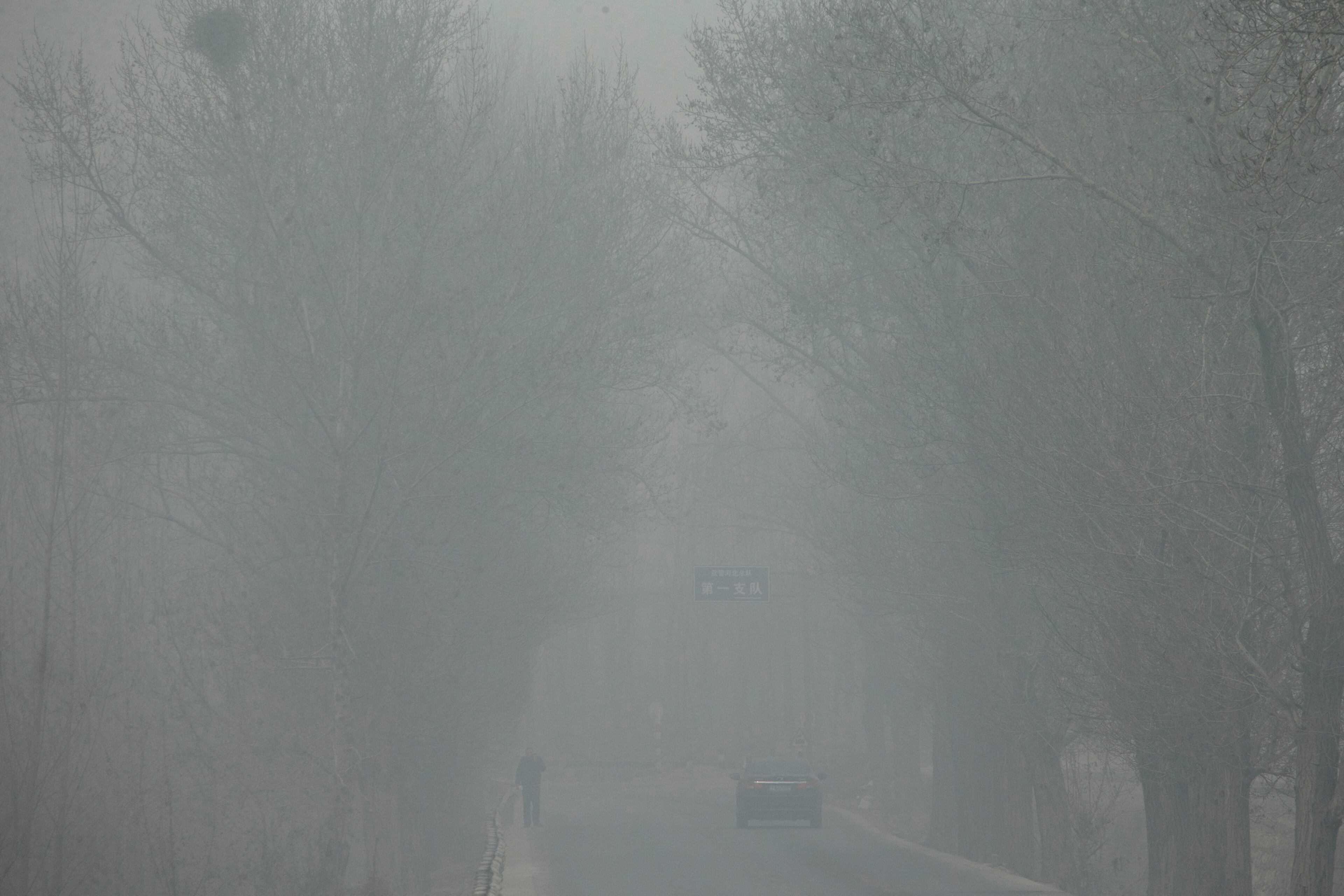 A man and a car travelling on a road are obscured in heavy haze on a severely polluted day in Pingshan county of Shijiazhuang, in northern China's Hebei province, Wednesday, Feb. 26, 2014. Chinese President Xi Jinping braved Beijing's choking smog Tuesday, making an unannounced visit to a trendy alley and sitting with residents in his latest public relations effort to be seen as a man of the people.