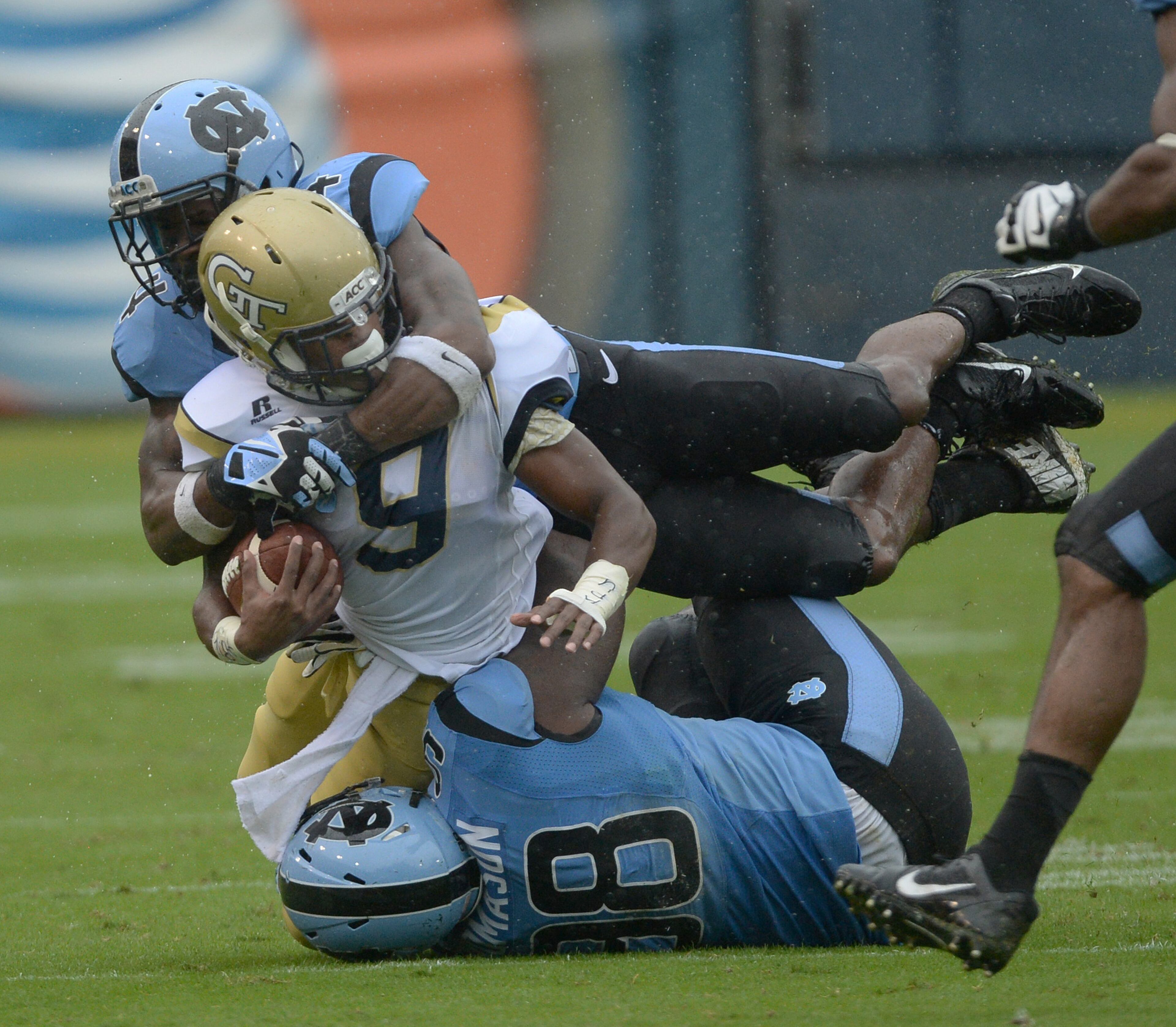 Georgia Tech's Tony Zenon (9) is tackled by North Carolina's Jabari Price (4) and Justin Thomason (98) in Bobby Dodd Stadium on Saturday, September 21, 2013. Tech won the game 28 to 20.