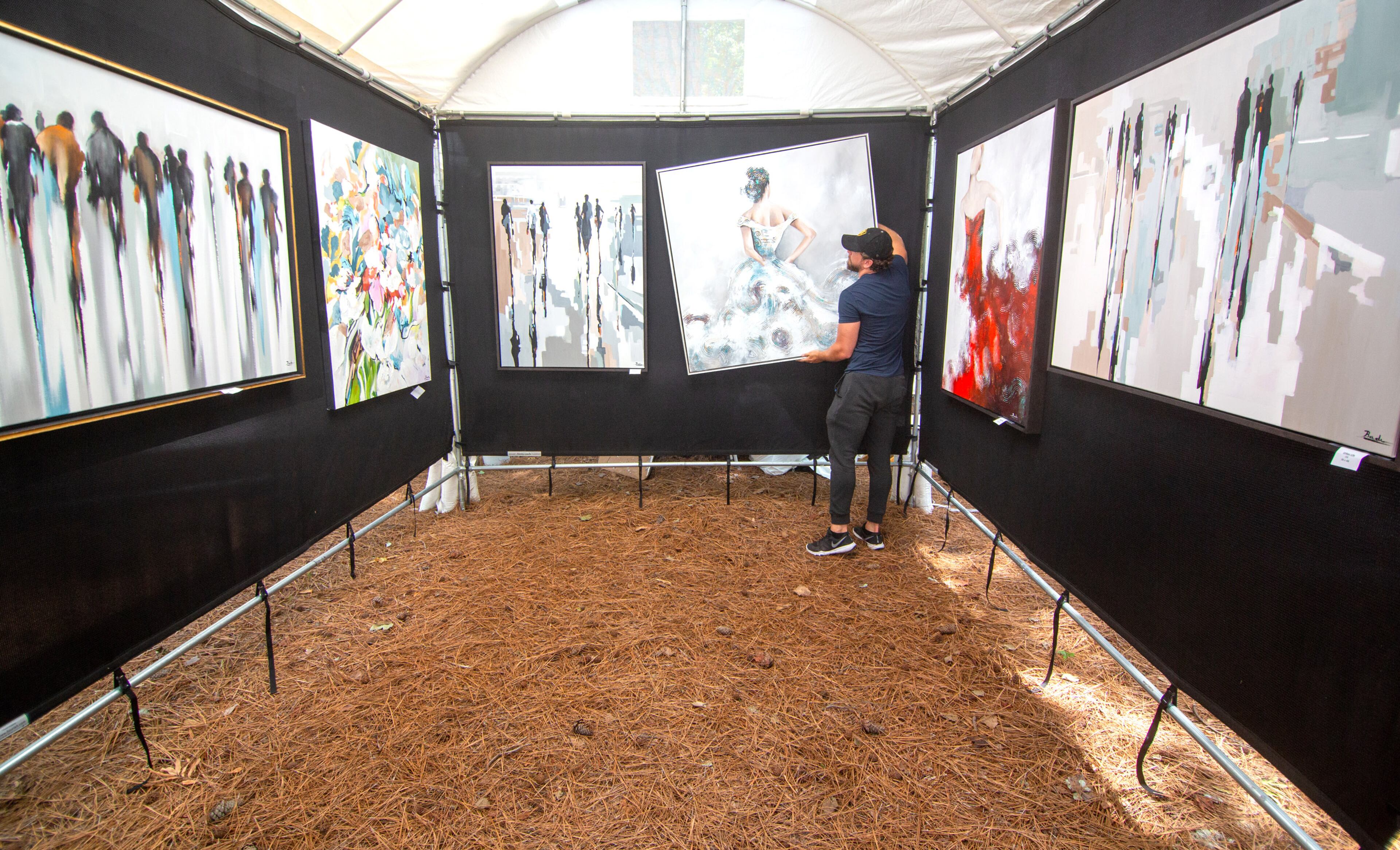 Amine Badr straightens one of his paintings while waiting for customers during the Roswell Spring Arts and Crafts Festival on Sunday, June 13, 2021. (Photo: Steve Schaefer for The Atlanta Journal-Constitution)