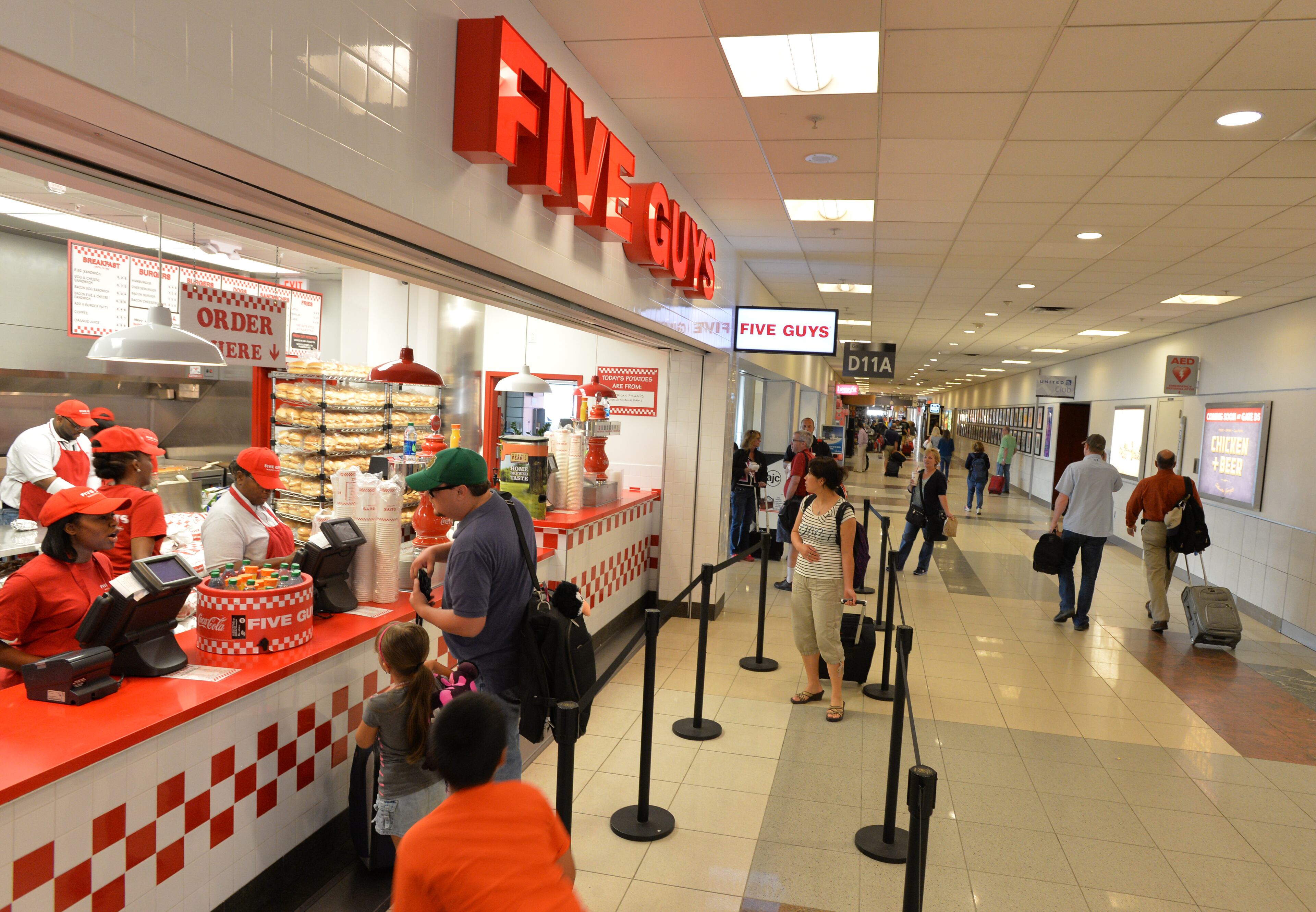 LEDE June 24, 2014 Atlanta - Airport travelers walk past one of newer restaurants, Five Guys, in Concourse D, Hartsfield-Jackson Atlanta International Airport on Tuesday, June 24, 2014. Hartsfield-Jackson and Delaware North celebrate the newest additions to Concourse D, including local favorites GrindHouse Killer Burgers and Yoforia, and national brands 40/40 Club and Food Network Kitchen. HYOSUB SHIN / HSHIN@AJC.COM