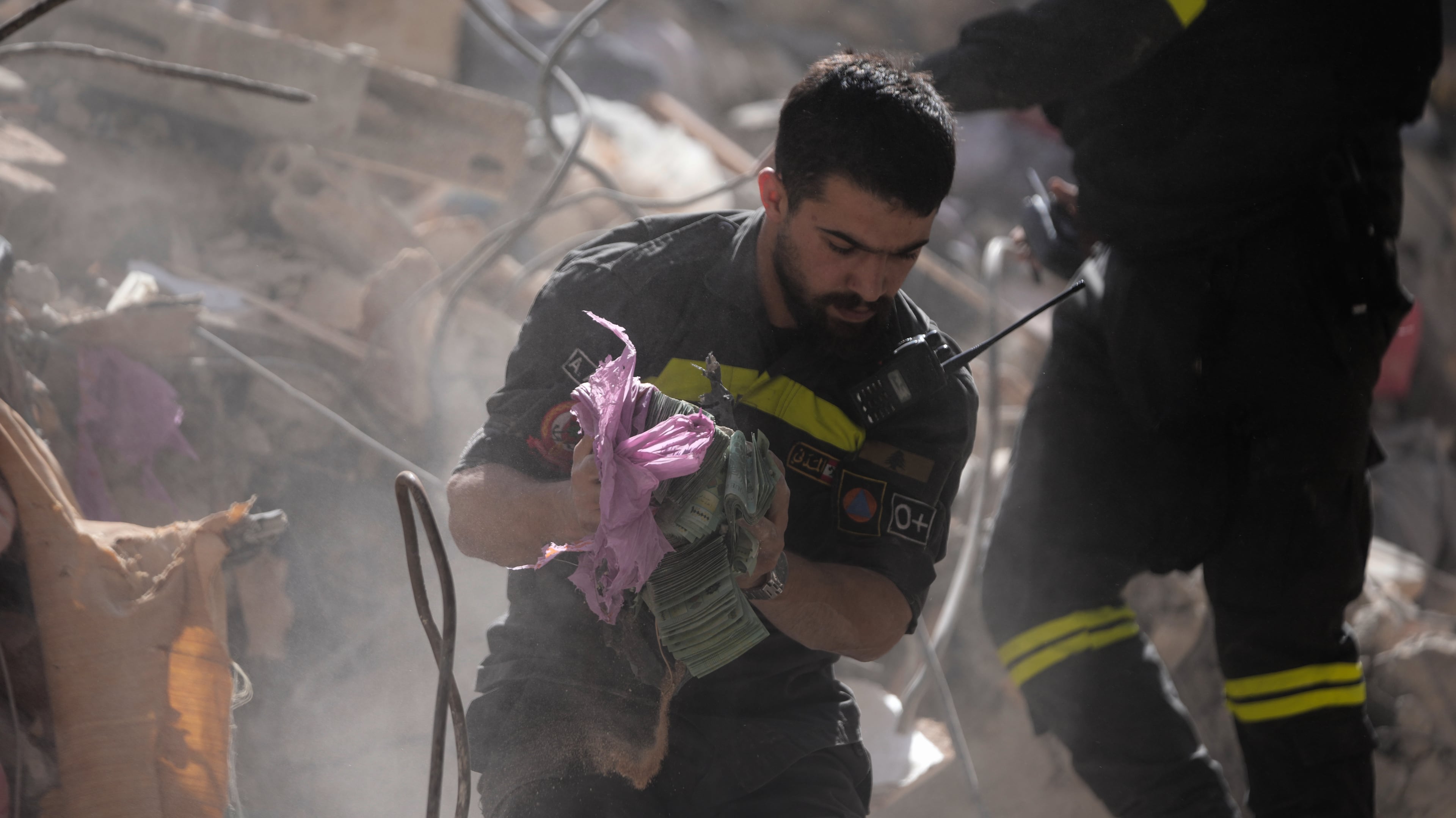 A rescue worker holds money recovered from the rubble of a destroyed building that was hit a day ahead in an Israeli airstrike in central Beirut, Lebanon, Thursday, April 9, 2026. (AP Photo/Hussein Malla)