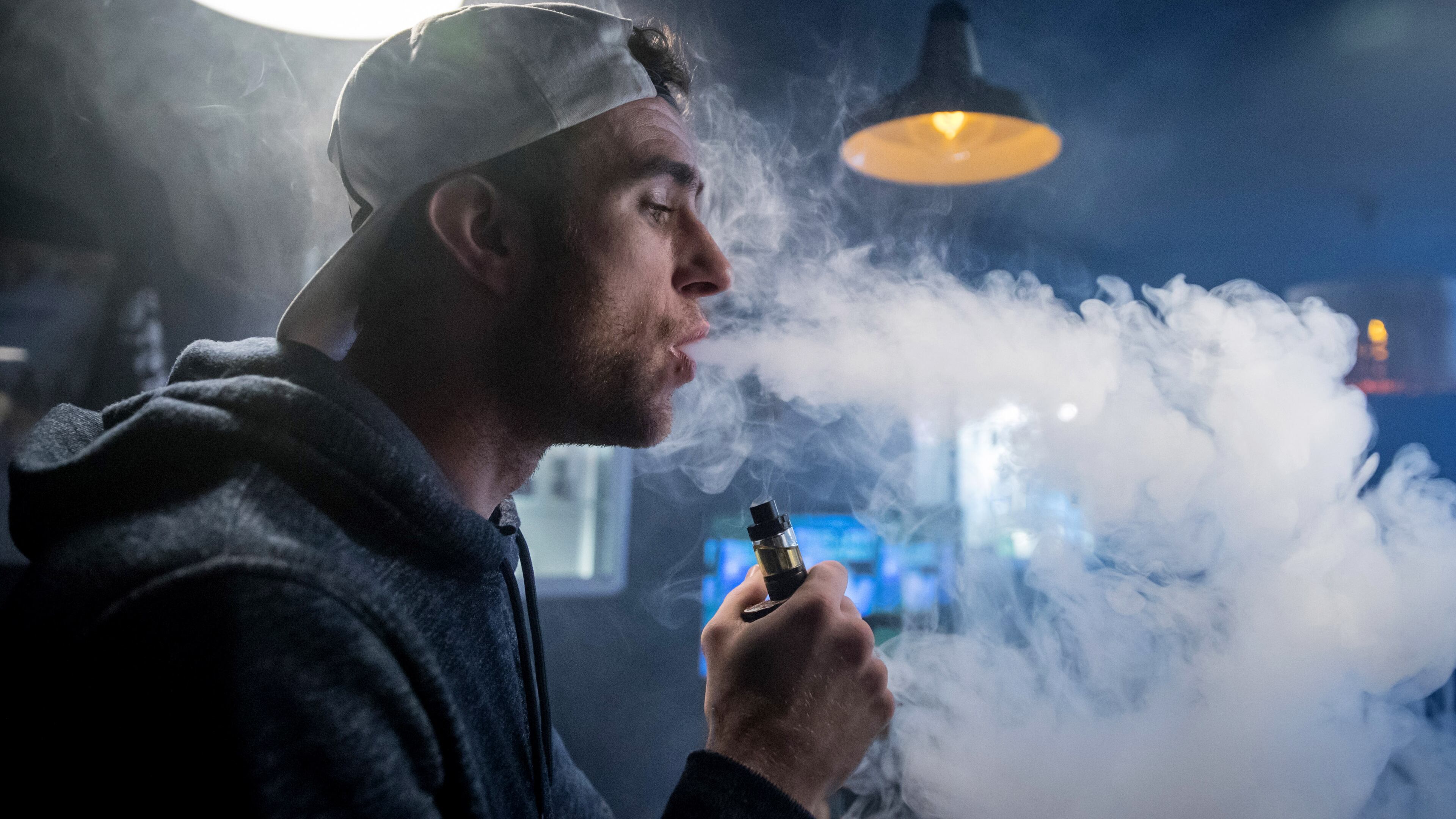 BRISTOL, ENGLAND - DECEMBER 30: Mitchell Baker who works at the Vapour Place a vaping shop in Bedminster, exhales vapor produced by an e-cigarette on December 30, 2016 in Bristol, England. Recent figures released by the e-cigarette industry has claimed that there as many as 1700 vaping shops across the country, with two new ones opening each day catering for the estimated three million vapers in the UK. The popularity of e-cigarettes has boomed in the last ten years, as it is seen by many as a healthier alternative to traditional cigarettes, however some critics say the devices can carry the same risks as smoking especially as the long term affects are yet to be known.