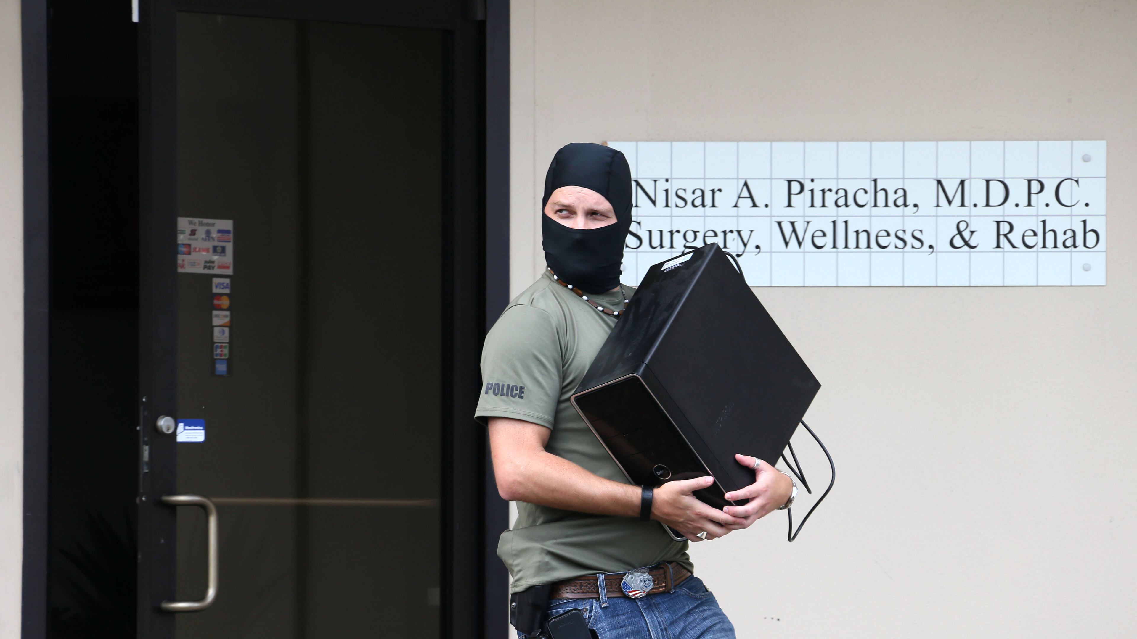 Masked DEA agents raided the office of Dr. Nisar S. Piracha, one of at least six Georgia doctors sent to prison this year for drug violations. BOB ANDRES / BANDRES@AJC.COM