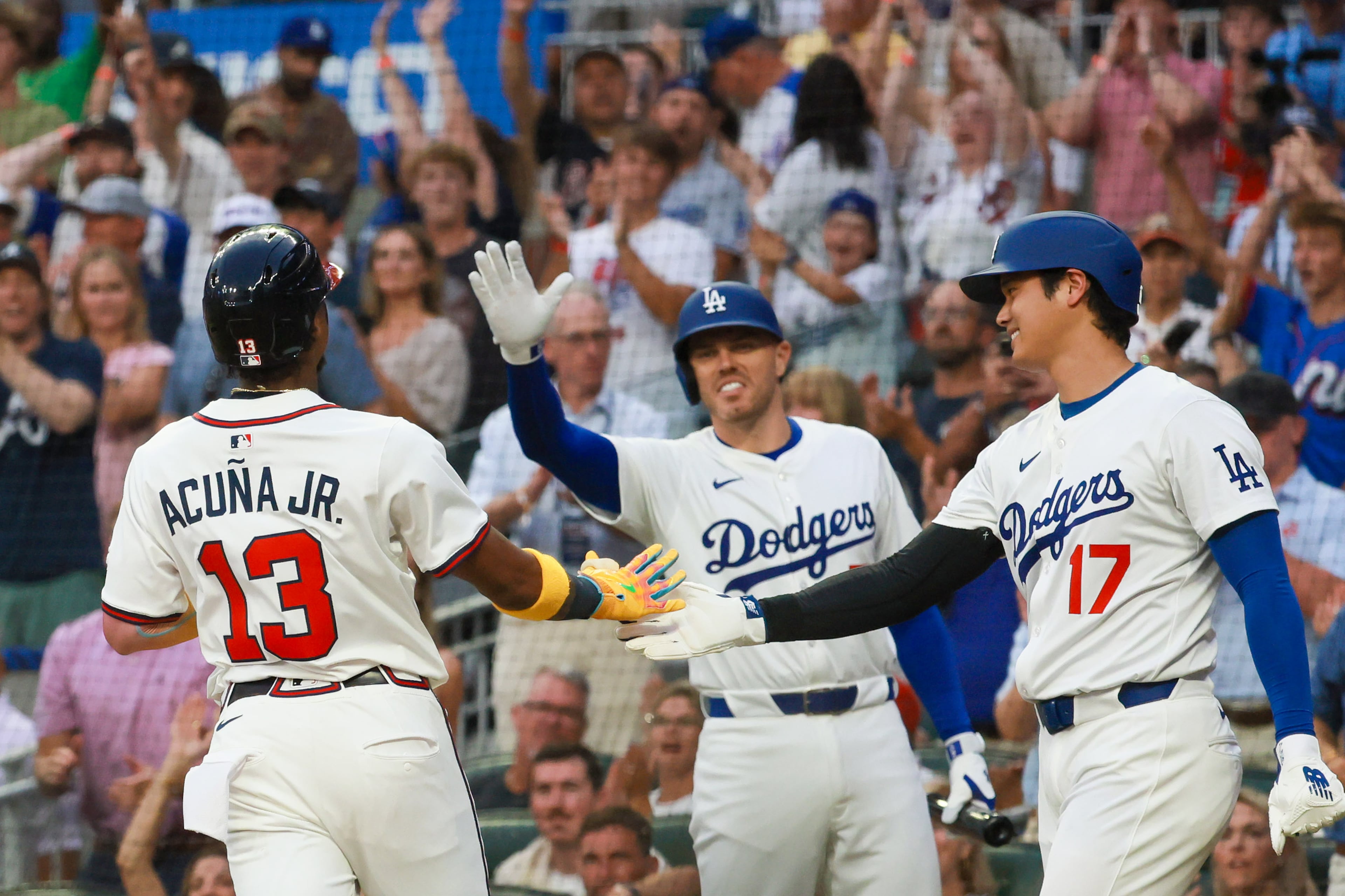 National League baserunner Ronald Acuña Jr., of the Atlanta Braves is greeted by former teammate Freddie Freeman of the Los Angeles Dodgers after scoring against the American League during the first inning of the MLB All-Star Game at Truist Park in Atlanta on Tuesday, July 15, 2025. (Jason Getz/AJC)