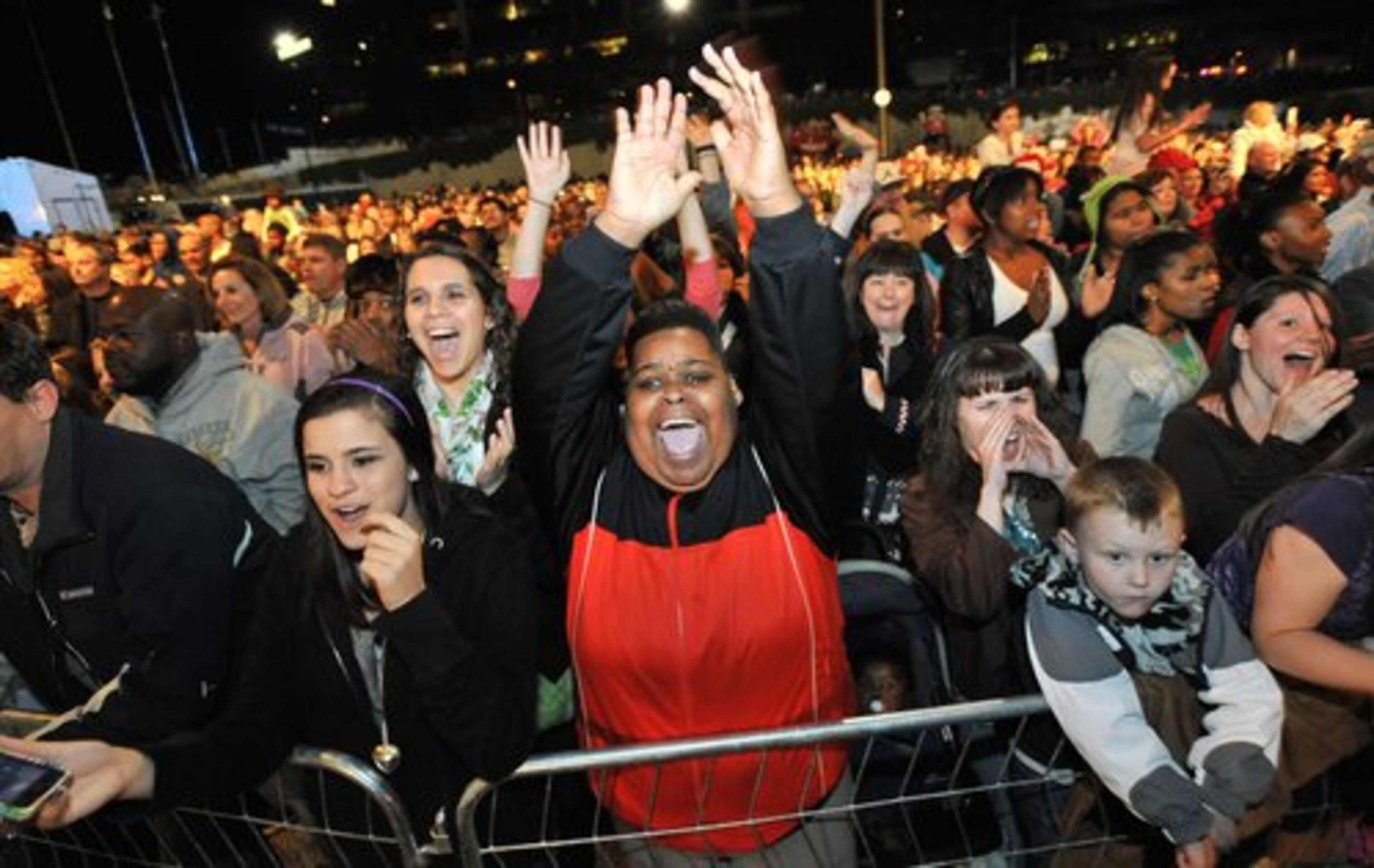 Camille Williams (center), of Atlanta, cheers as she listens to live performance during the Macy's Great Tree Lighting Show at Lenox Square Mall on Thursday, November 24, 2011.
