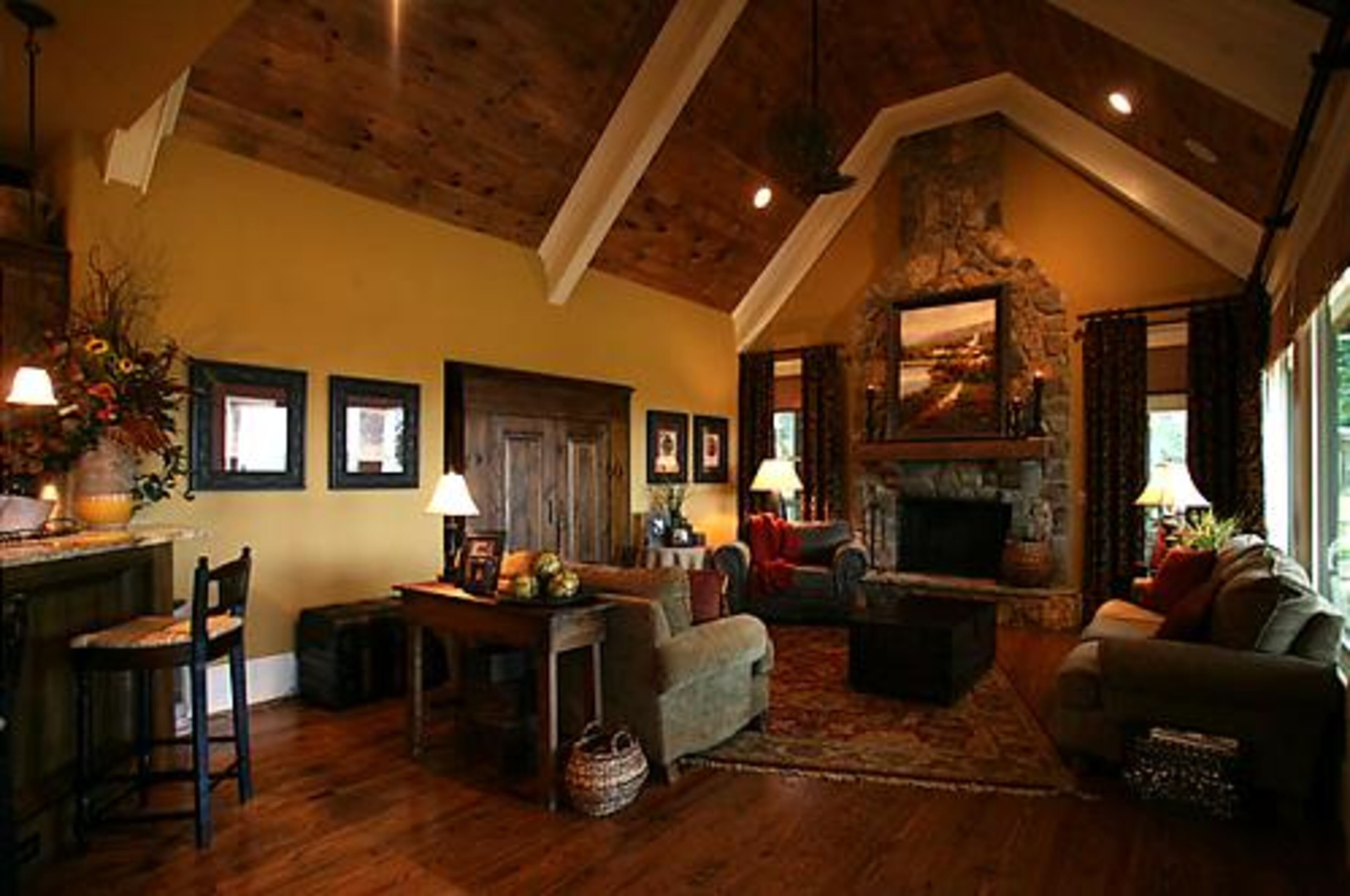 The Godfreys' family living room features a stone fireplace, exposed beams and high ceilings. The children can escape to the screened porch to the right of the fireplace. Overstuffed sofas give the room a cozy air.