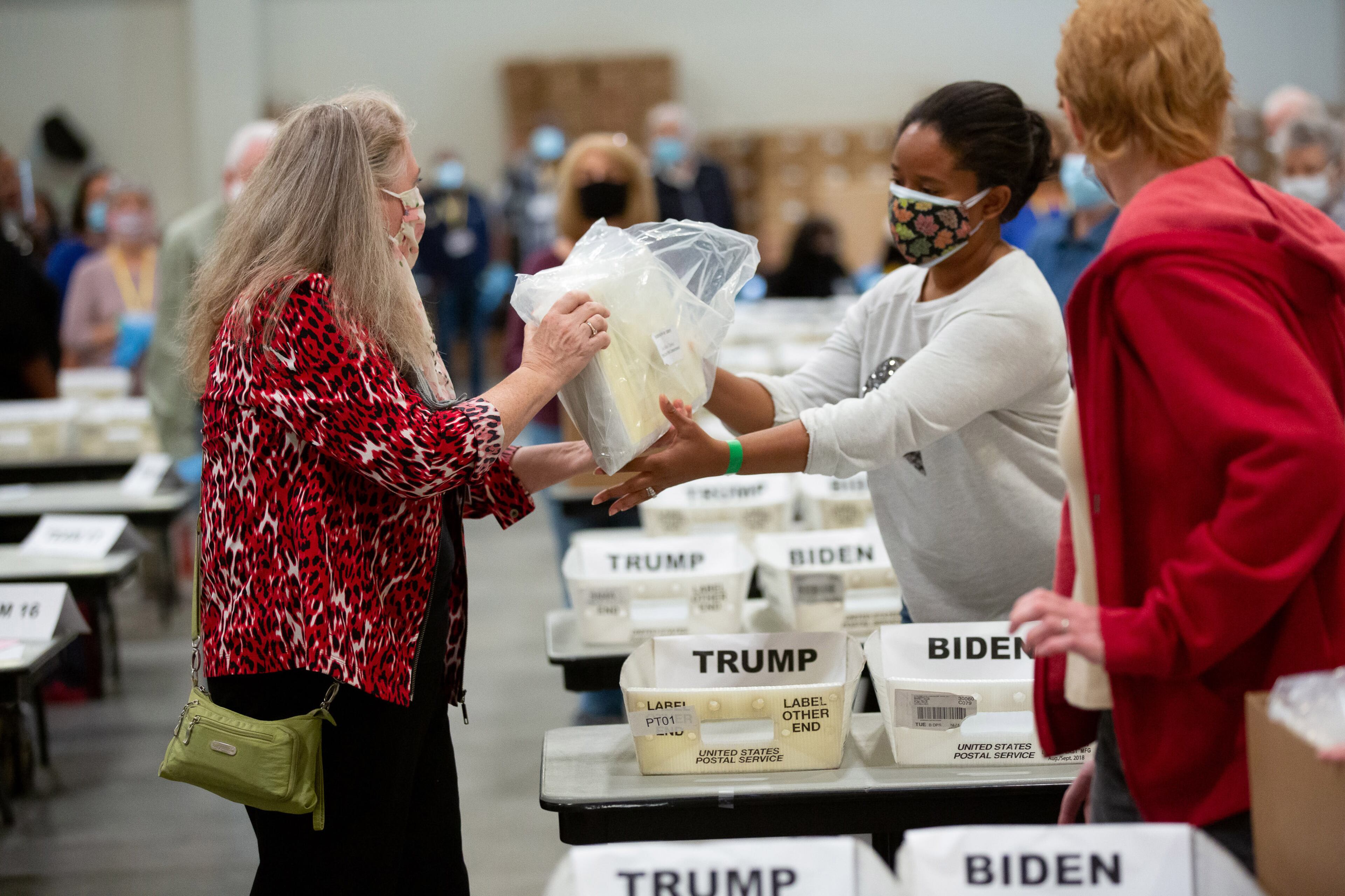 Allison Schaeffer (L) holds uncounted ballots as she walks the Cobb County election staff throw the recount process Friday at the Jim Miller Park Event Center in Marietta on November 13, 2020. STEVE SCHAEFER / SPECIAL TO THE AJC