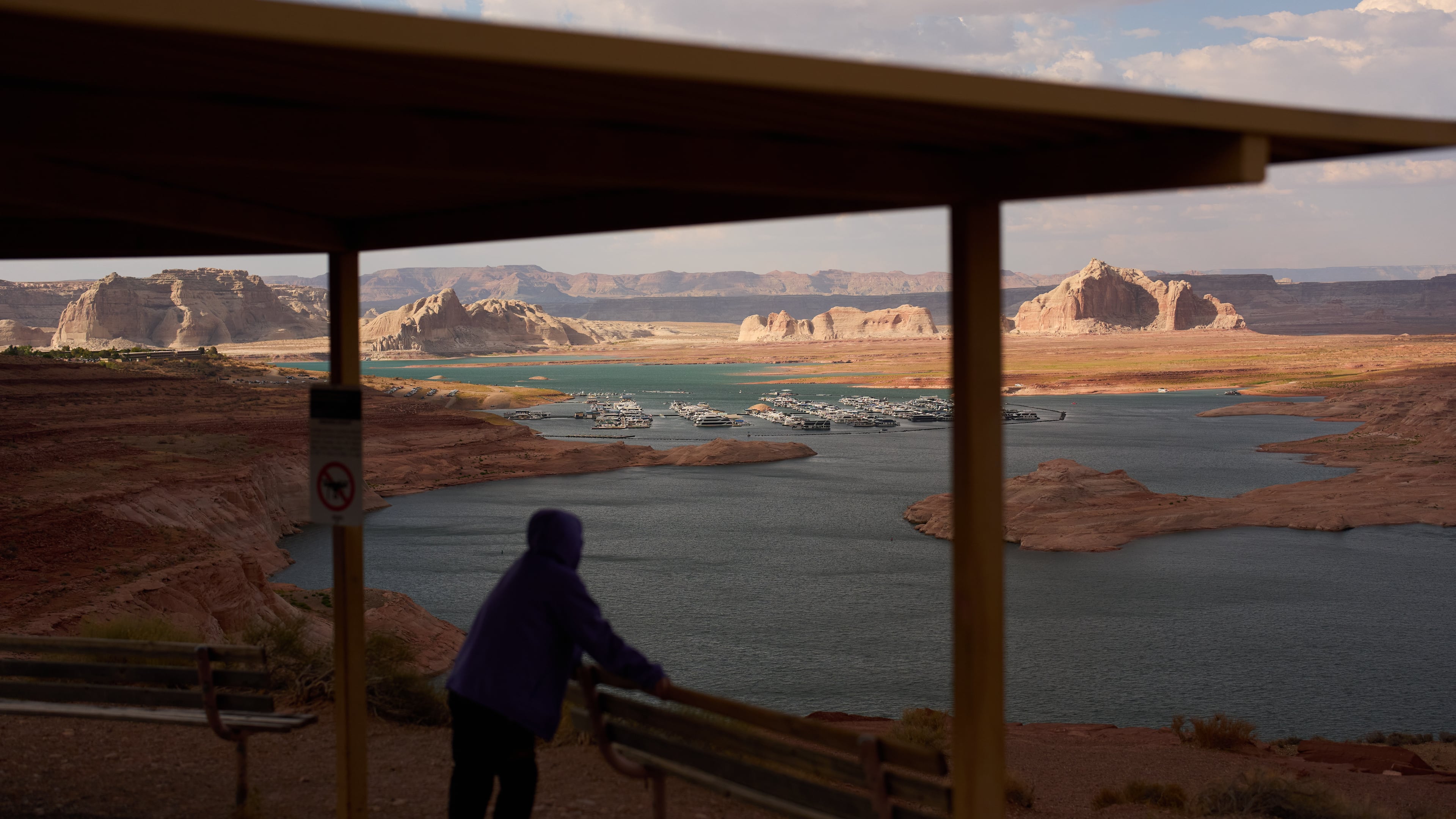 FILE - A person stands at an overlook near the Wahweap Marina on Lake Powell at the Glen Canyon National Recreation Area, July 15, 2026, near Page, Ariz. (AP Photo/John Locher, File)