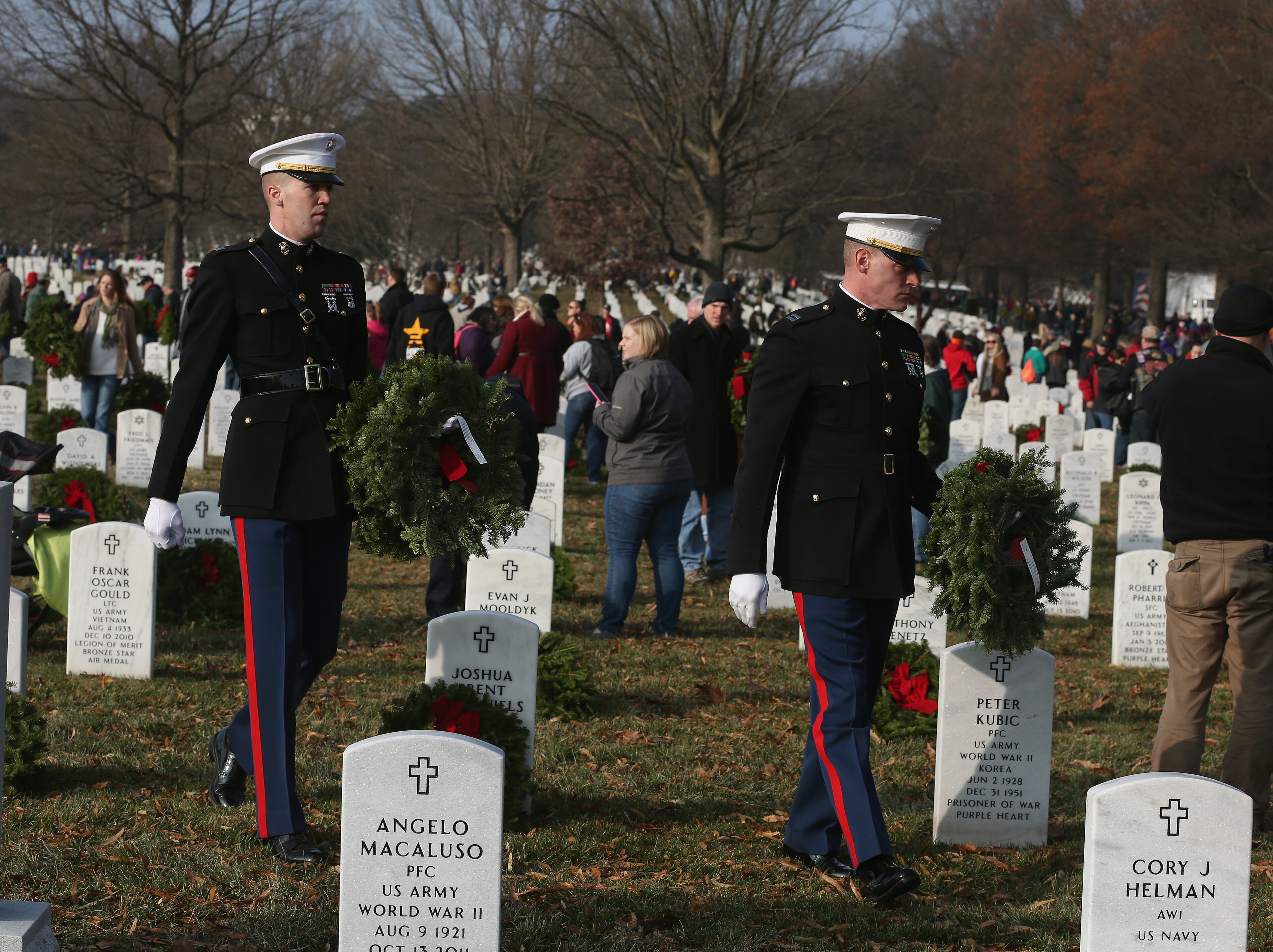 ARLINGTON, VA - DECEMBER 13: US Marines Capt. Benjamin O'Donnell (R) and Capt. Mike Harvey (L) look for a Marine graves to place wreaths on during the National Wreaths Across America Day at Arlington National Cemetery, December 13, 2014 in Arlington, Virginia. Volunteers placed wreaths throughout the entire cemetery in honor of Arlingtons 150th anniversary. (Photo by Mark Wilson/Getty Images)