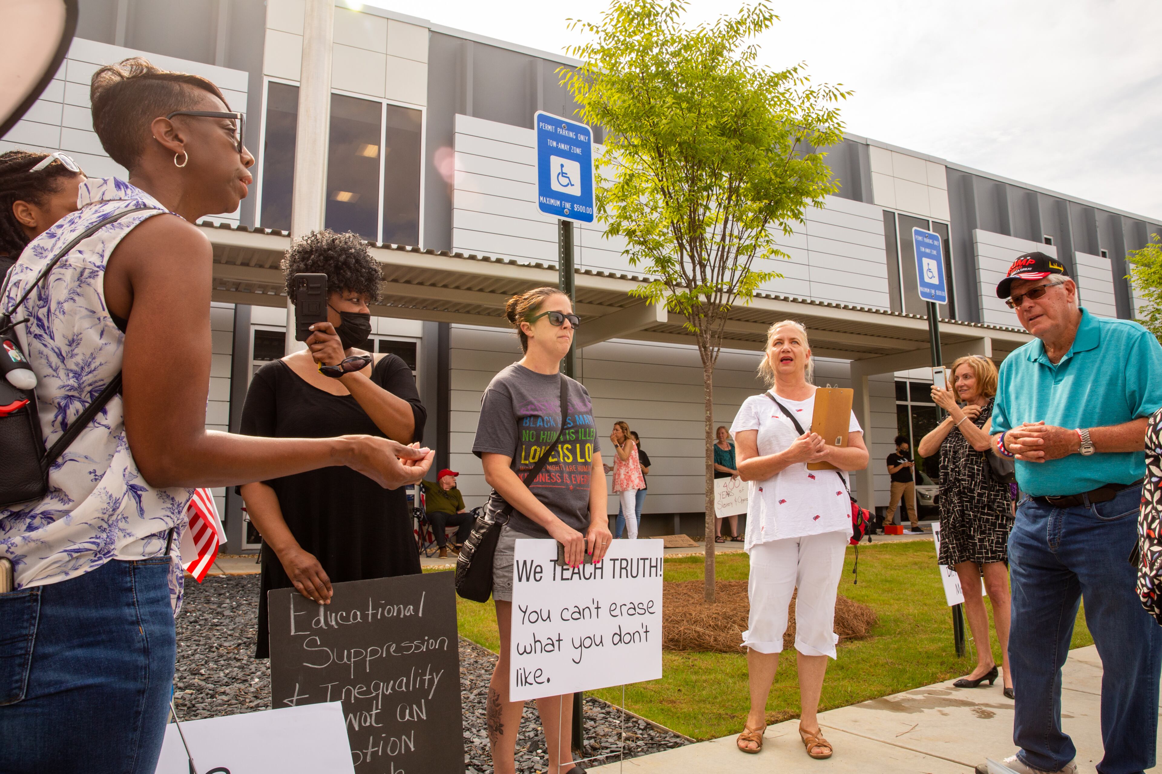Before a Cobb County of Education board meeting begins, Dawn Mann, far left, debates with Leroy Emkin, far right. Teachers, parents and local residents gather to voice their opinions on critical race theory and what Cobb County teaching and the reviews initiated by the school board Thursday, June 10, 2021. (Jenni Girtman for The Atlanta Journal Constitution)