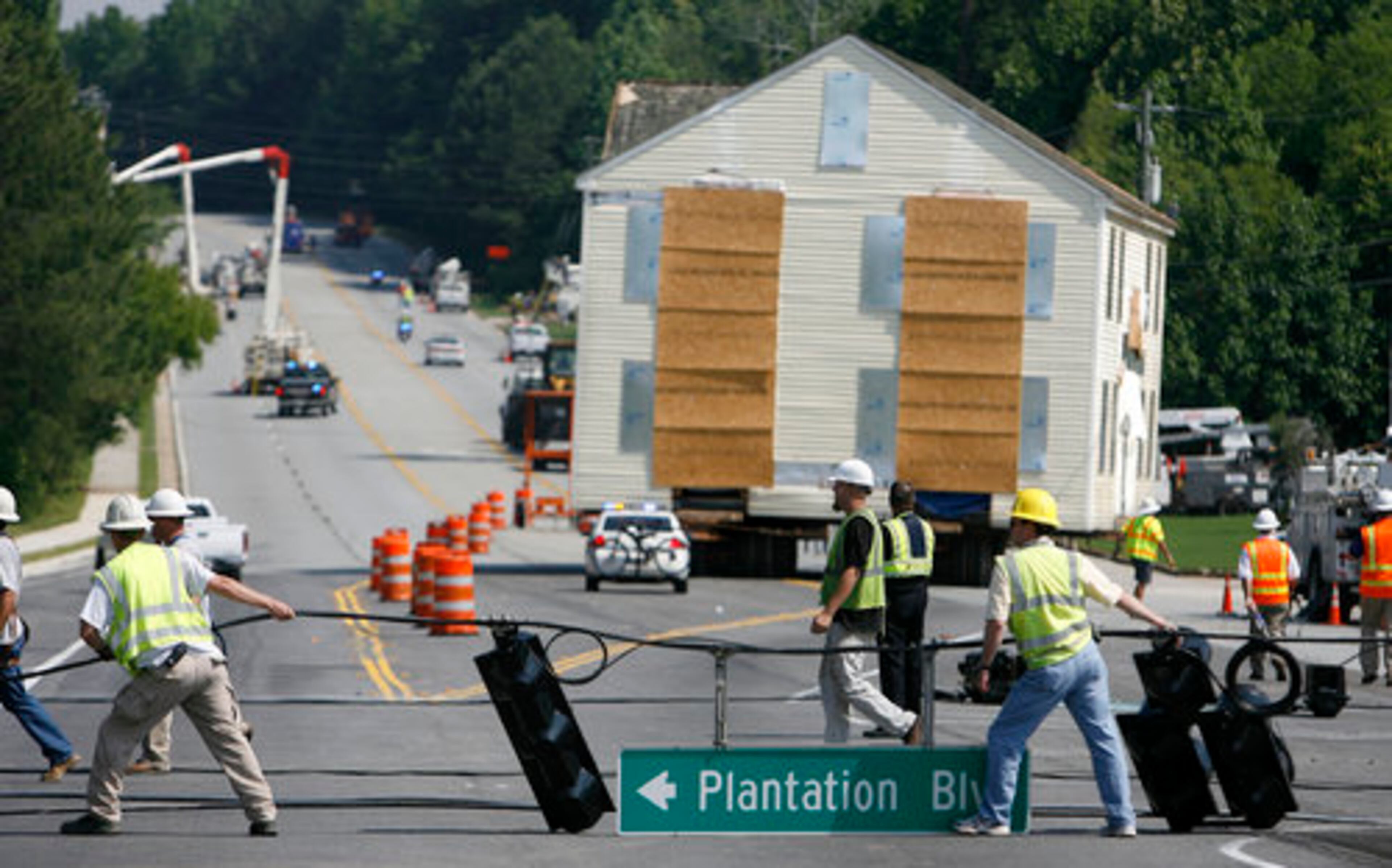 Utility crews remove and reconnect wires and traffic signals while the move of the Adair House progresses along Grayson Highway.