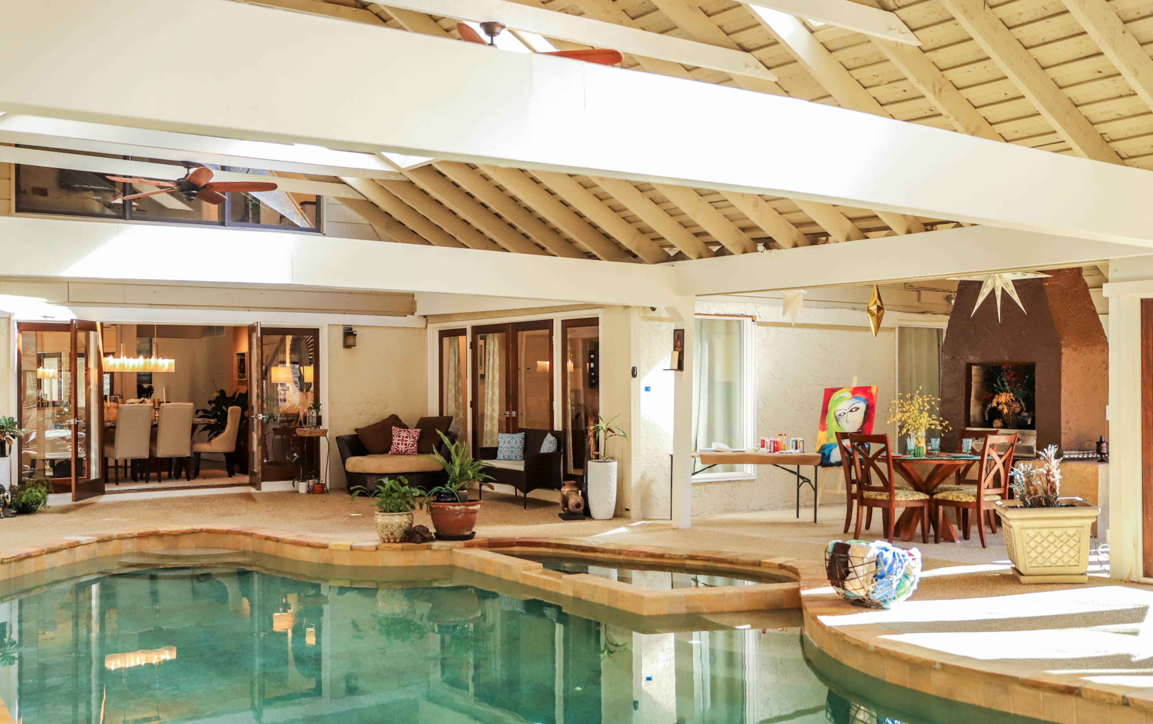 The master suite, dining room and front entry all open up to the pool room, making it a central location for the family and for entertaining. A small table and Sugandha Rosenhaft's art easel show the many uses the fireside room offers, as a party space and an art studio.