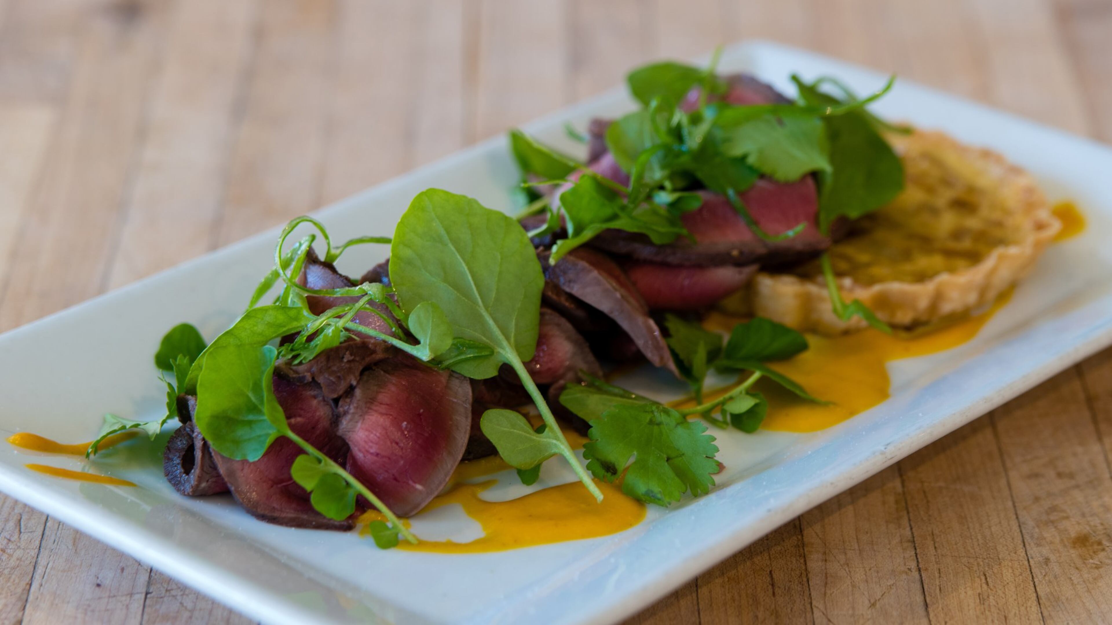 Charcoal-grilled beef heart with a sweet onion tart at Gunshow. CONTRIBUTED BY HENRI HOLLIS