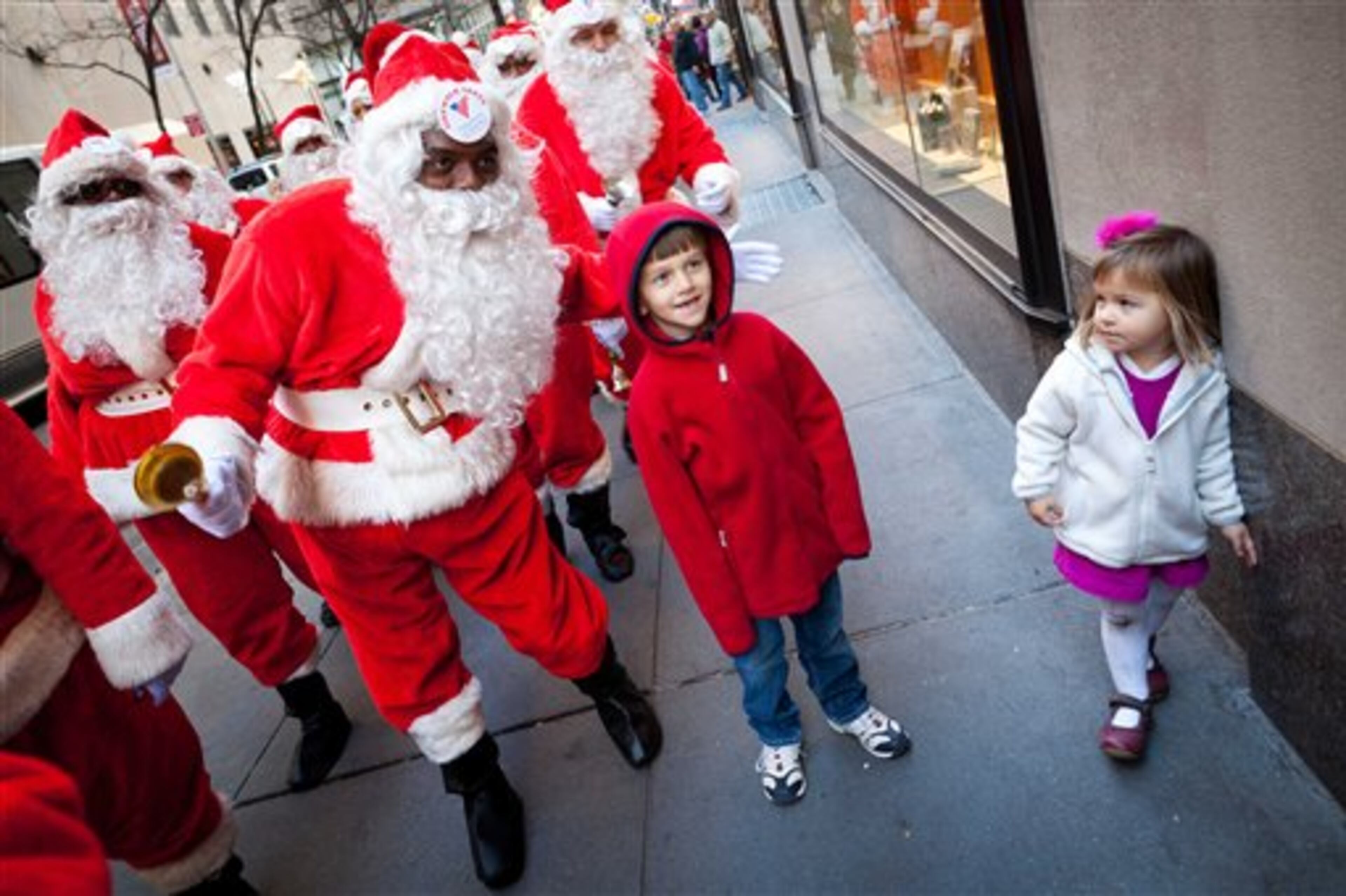 A charity worker dressed as Santa Claus poses for a photo with a boy during a march of Sidewalk Santas, Friday, Nov. 25, 2011, in New York. Volunteers of America held it's 109th annual Sidewalk Santa Parade on the busiest shopping day of the year to raise money for a holiday food voucher program for needy residents. (AP Photo/John Minchillo)