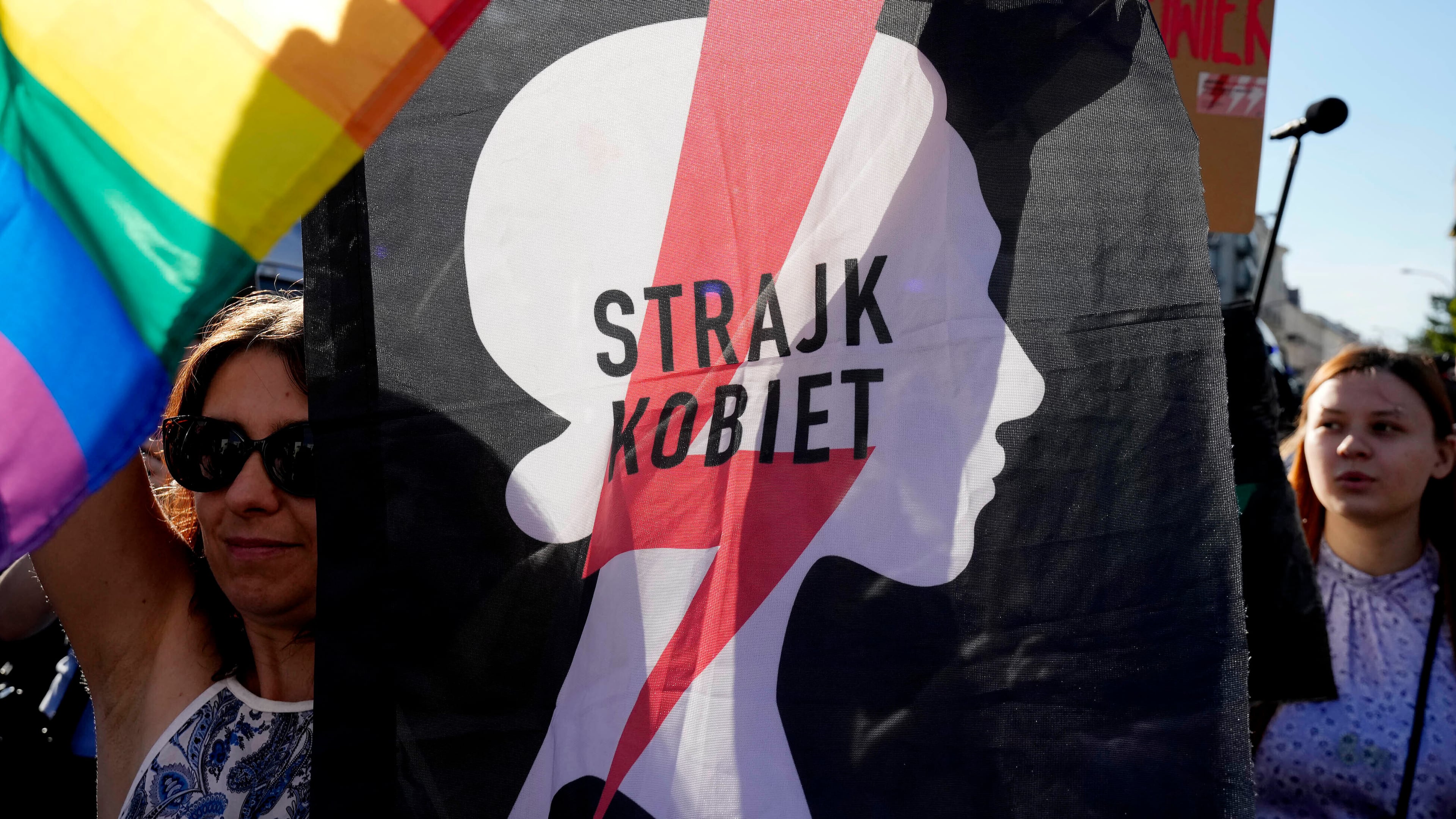 FILE - A woman with the sign of a women's rights organization and with a pro-LGBT+ rights flag take part in a protest in Warsaw, Poland, Tuesday, July 23, 2024. (AP Photo/Czarek Sokolowski, File)