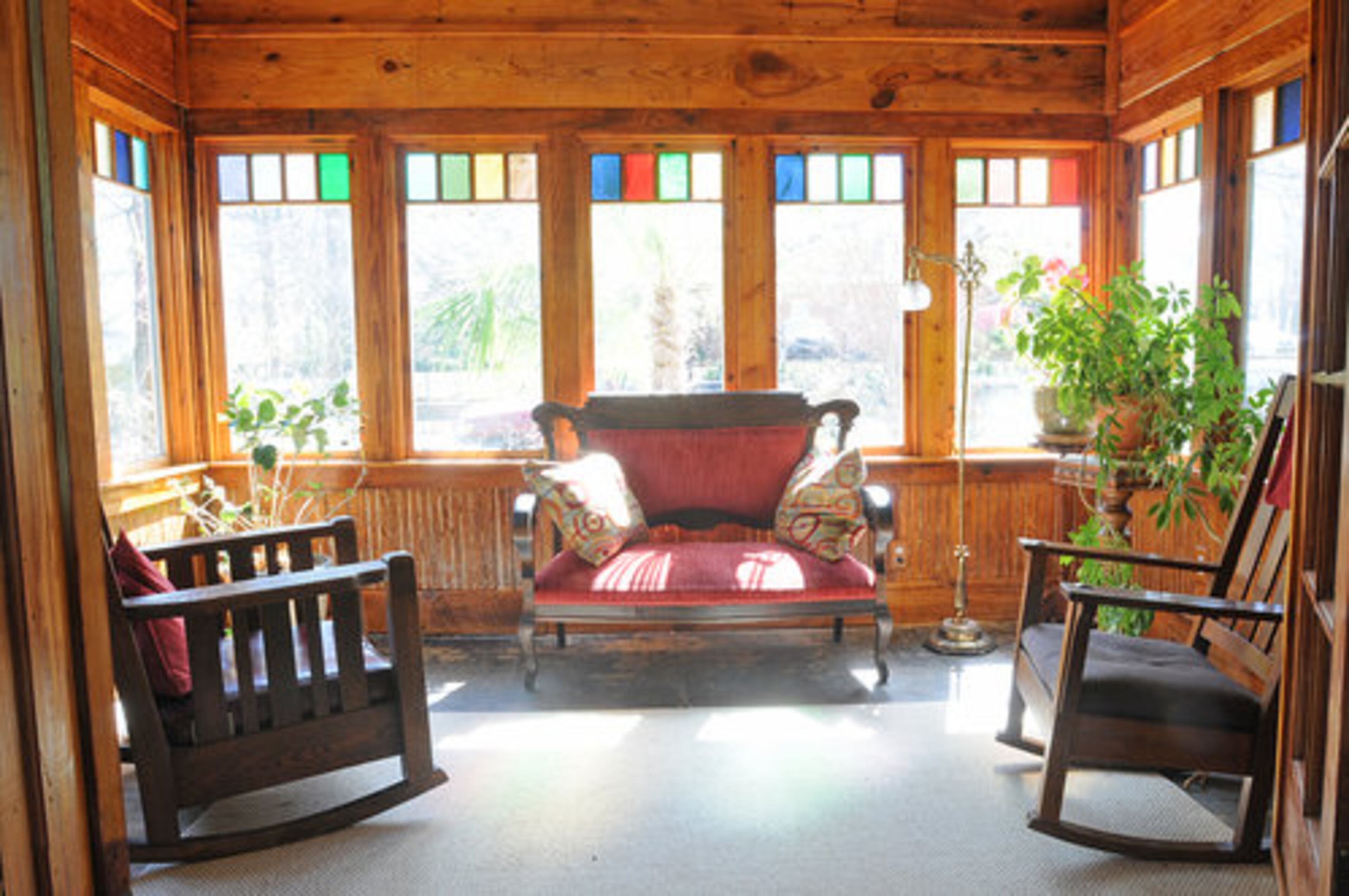 The sun room: "When we purchased the house, this room had been converted to a small ugly kitchen," said homeowner Kara O'Brien. "The original windows were gone or rotted and there was a dropped water soaked accoustical ceiling. We took down the beaded board wainscotting and ceiling beaded board, insulated and reframed everything, planed the boards and reinstalled them. We milled the windows from heart of pine beams from the back of the house, and installed stained glass squares."