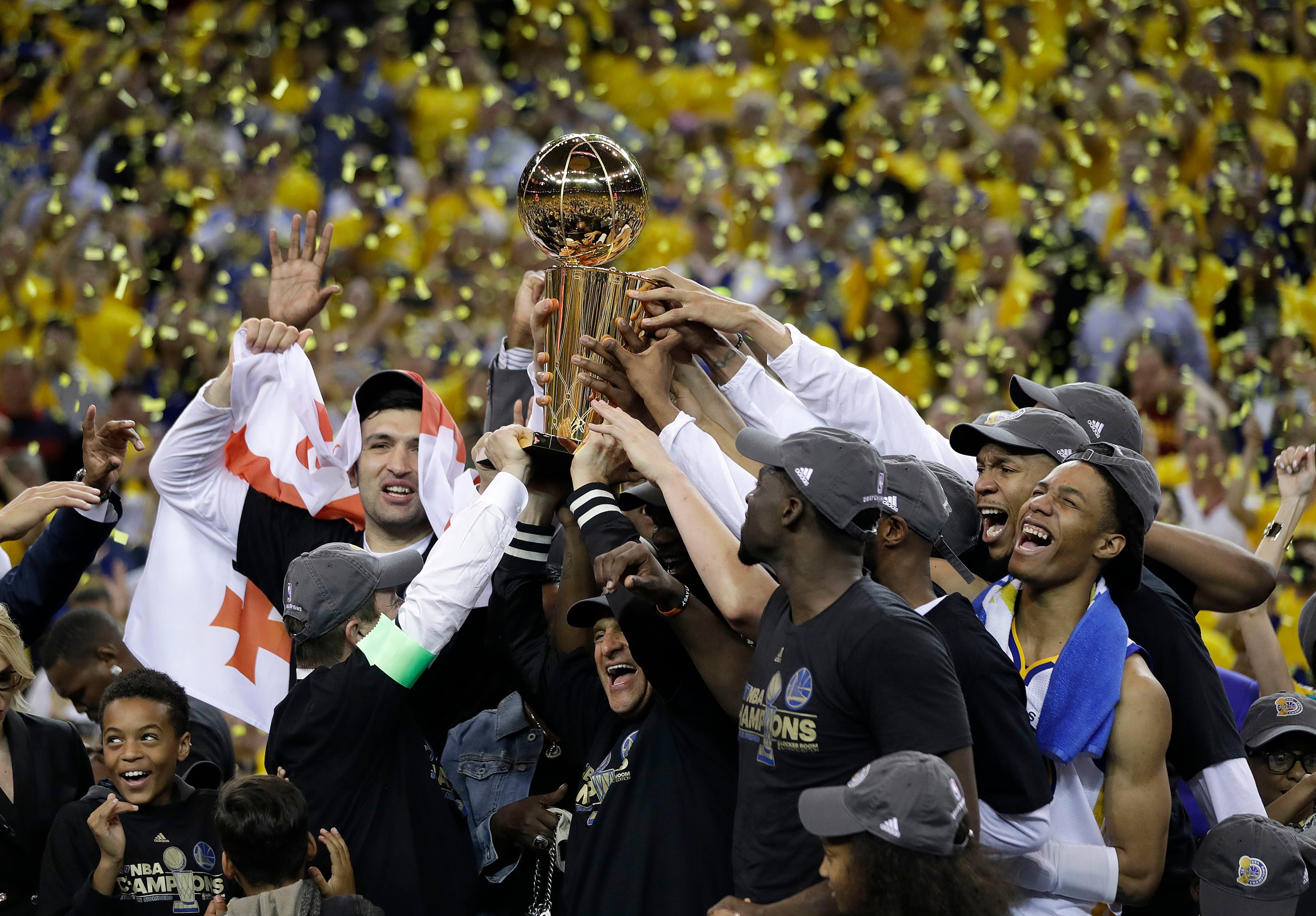 Golden State Warriors players, coaches and owners hold up the Larry O'Brien NBA Championship Trophy after Game 5 of basketball's NBA Finals between the Warriors and the Cleveland Cavaliers in Oakland, Calif., Monday, June 12, 2017. The Warriors won 129-120 to win the NBA championship. (AP Photo/Marcio Jose Sanchez)
