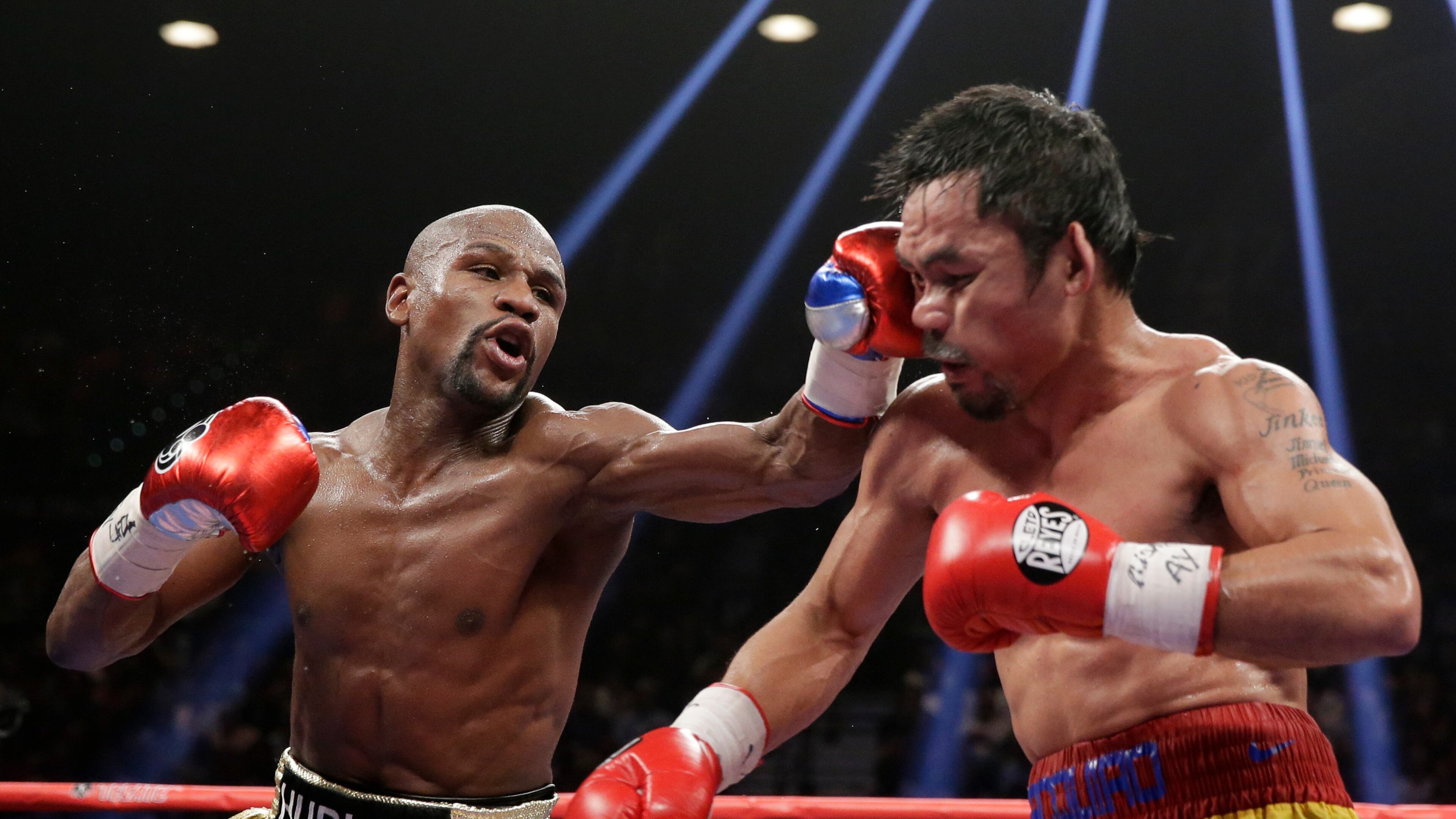 FILE - Floyd Mayweather Jr., left, hits Manny Pacquiao, from the Philippines, during their welterweight title fight on May 2, 2015, in Las Vegas. (AP Photo/Isaac Brekken, File)
