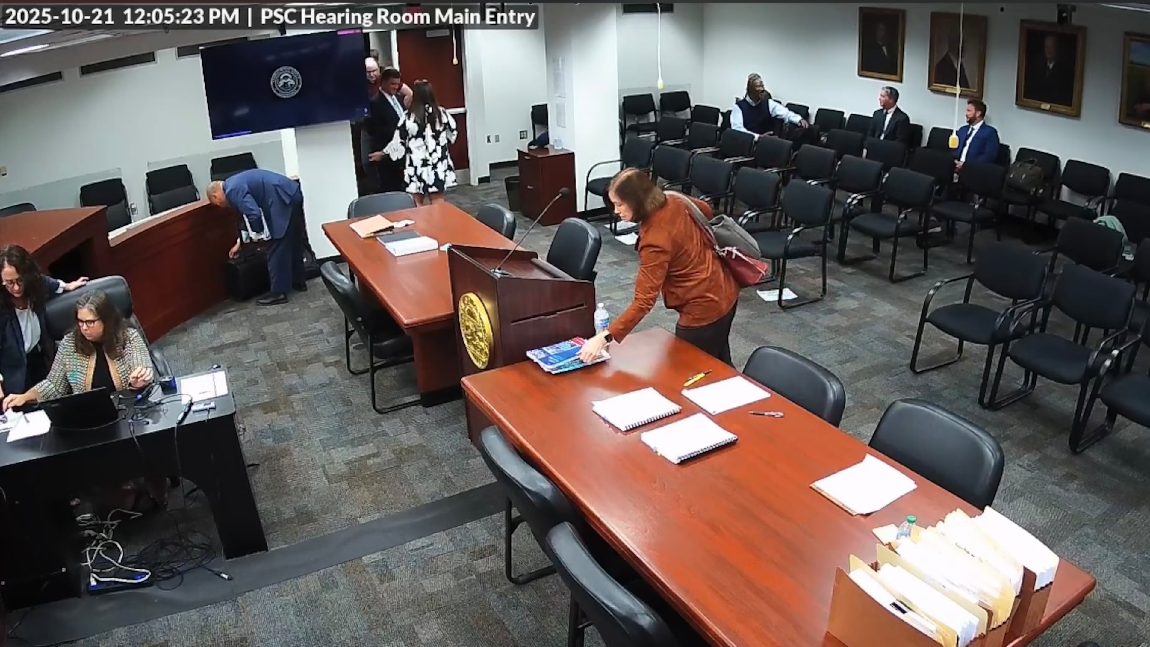 A screengrab from video taken inside the Georgia Public Service Commission hearing room shows former PSC candidate Patty Durand pick up a copy of allegedly trade secret information belonging to Georgia Power. Police say Durand put the booklet into her purse and left the room during a recess in a hearing on Tuesday, Oct. 21, 2025. Durand was charged with theft of trade secrets, records show. On Wednesday, Fulton County District Attorney Fani Willis told the court she will not prosecute Durand. (Video provided by the Georgia Public Service Commission.
