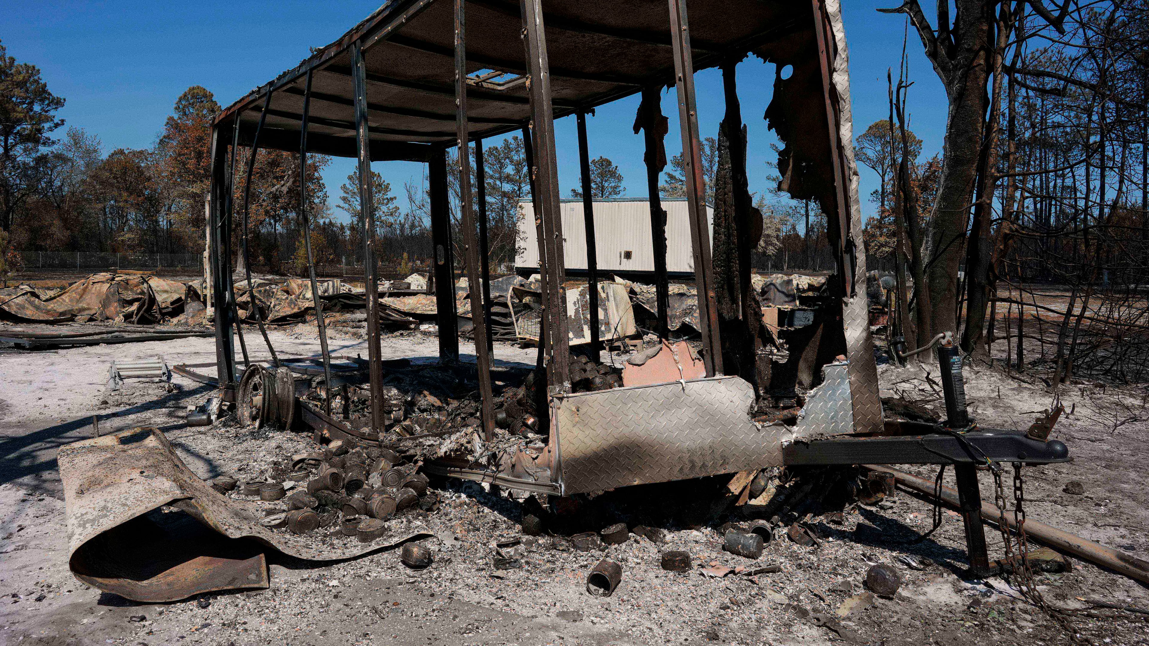 A burned trailer sits near a destroyed home as the Brantley Highway 82 fire burns, Thursday, April 23, 2026, near Nahunta, Ga. (AP Photo/Mike Stewart)