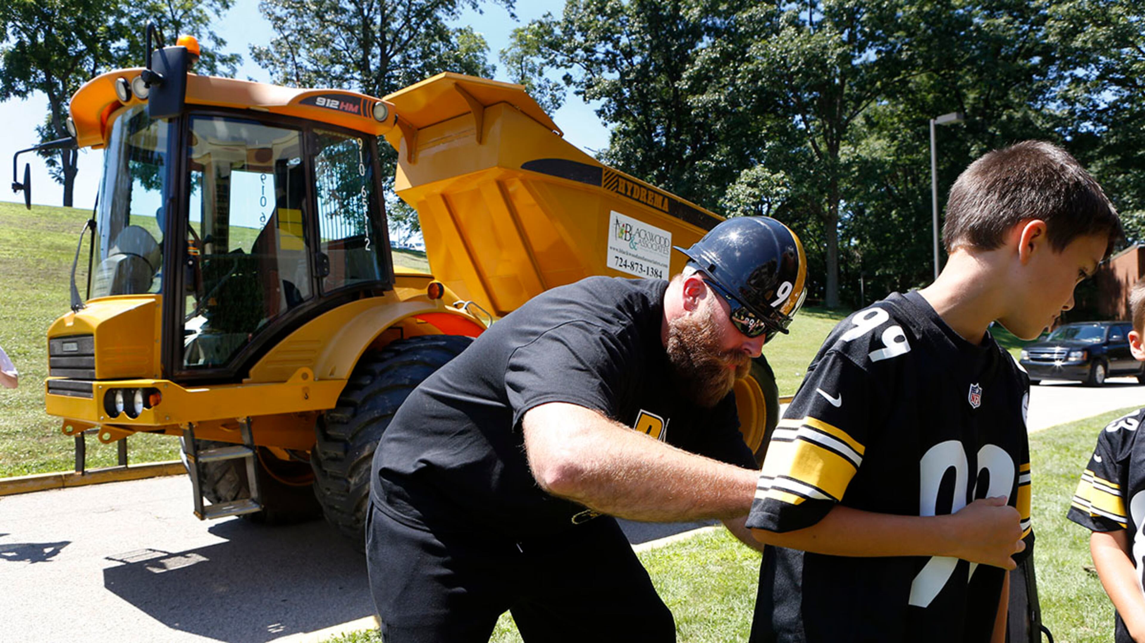Pittsburgh Steelers defensive end Brett Keisel signs a jersey for a young fan in front of the off-road dump truck he drove up the driveway toward the dormitories at his arrival for the start of their training camp at the team training facility in Latrobe, Pa.