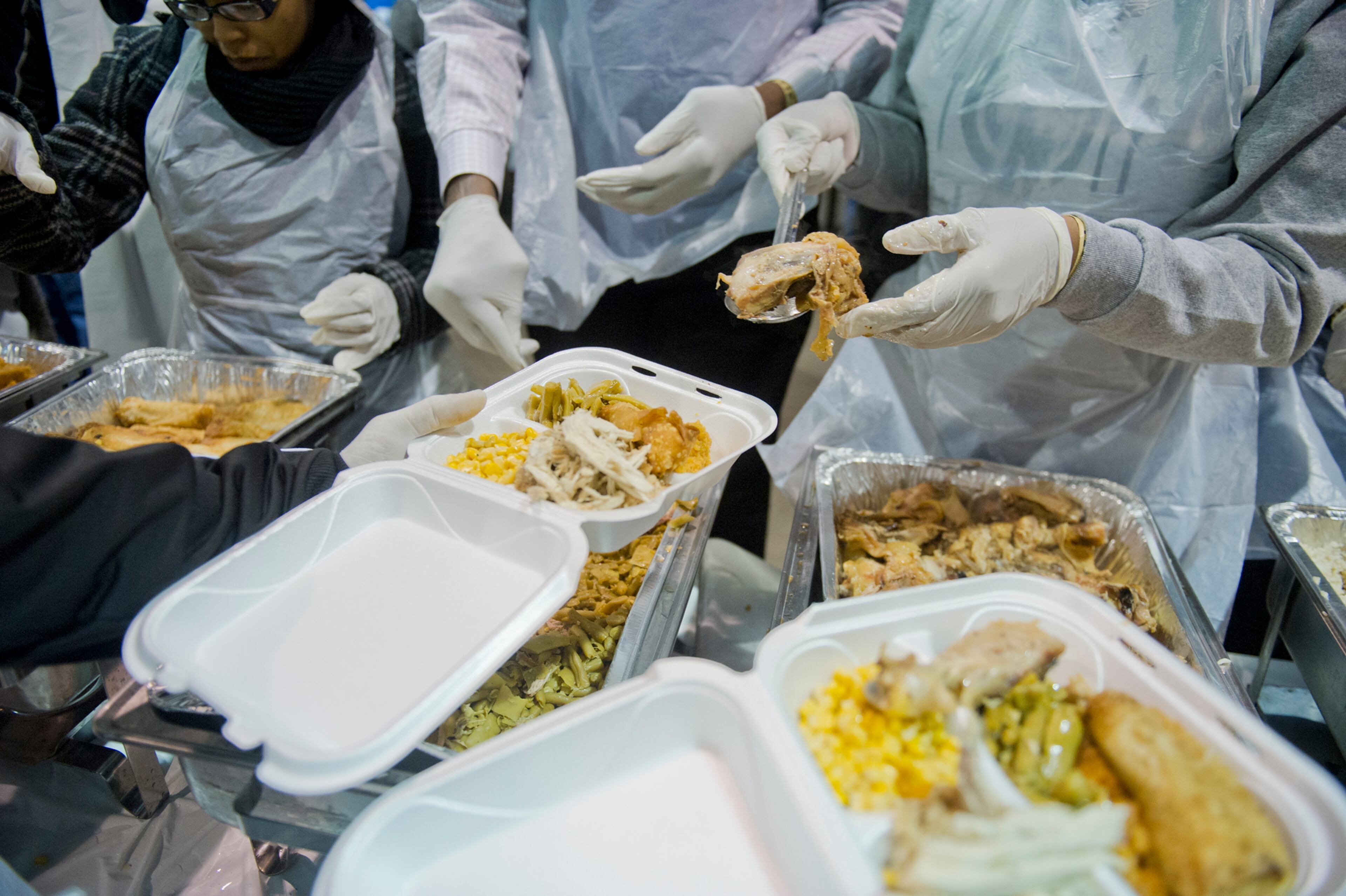 Carrie Mutombo (center) places pieces of meat onto trays during the Hosea Feed the Hungry and Homeless annual Thanksgiving meal at the Georgia World Congress Center in Atlanta on Nov. 28, 2013.