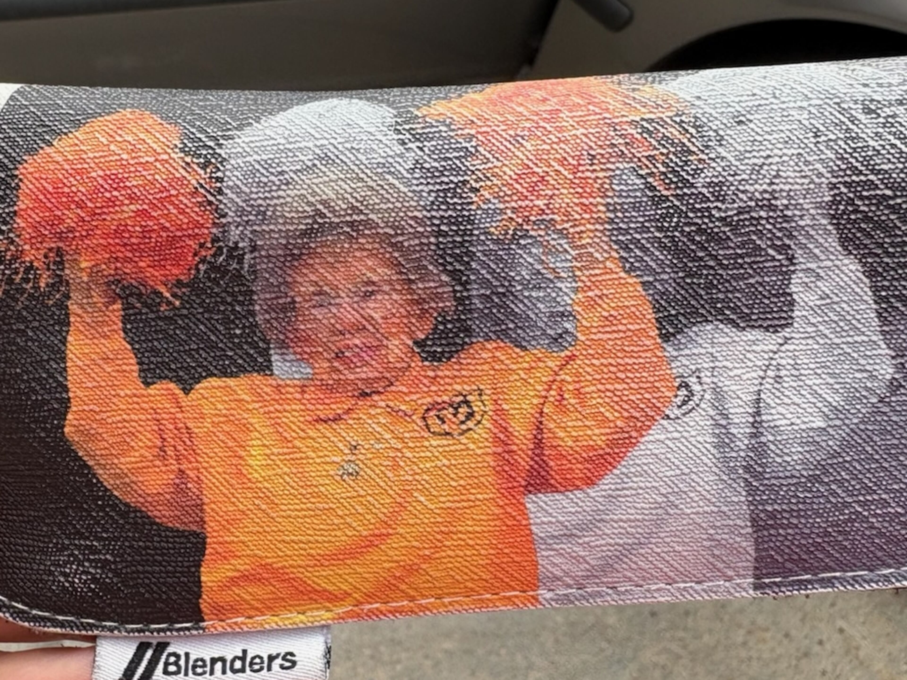 An eyeglass sleeve with an image of University of Colorado fan Peggy Coppom, aka "Miss Peggy." Buffaloes coach Deion Sanders arranged a name, image and likeness deal for Coppom with an eyewear maker which gives her $1 for each sleeve sold. The opposite side of the sleeve reads "I aint hard 2 find, either," a reference to Sanders' recruiting slogan "I ain't hard to find." (AJC photo by Ken Sugiura)