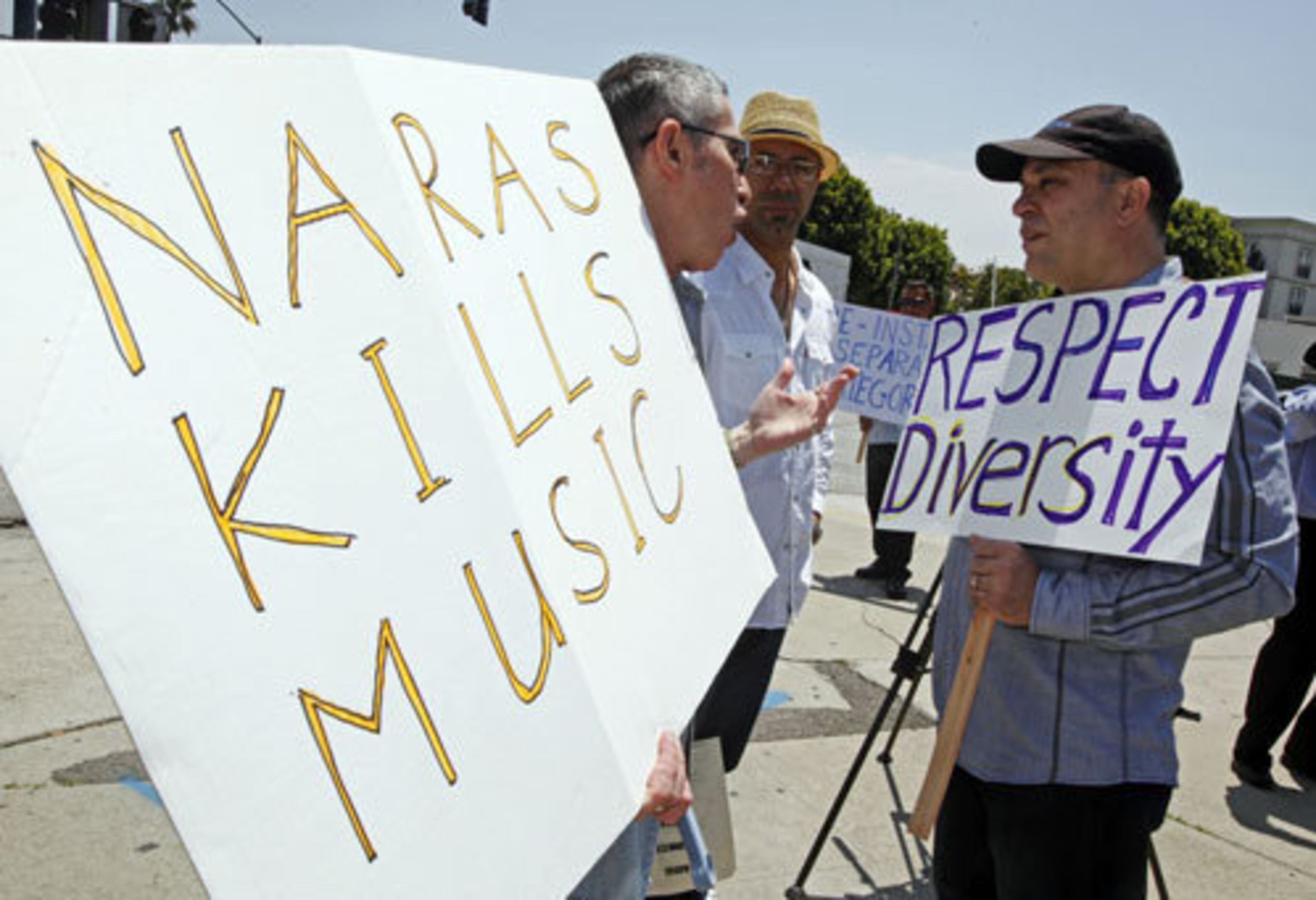 Two-time Grammy winner Oscar Hernandez, right, holds a "respect diversity" sign while he speaks with another demonstrator.