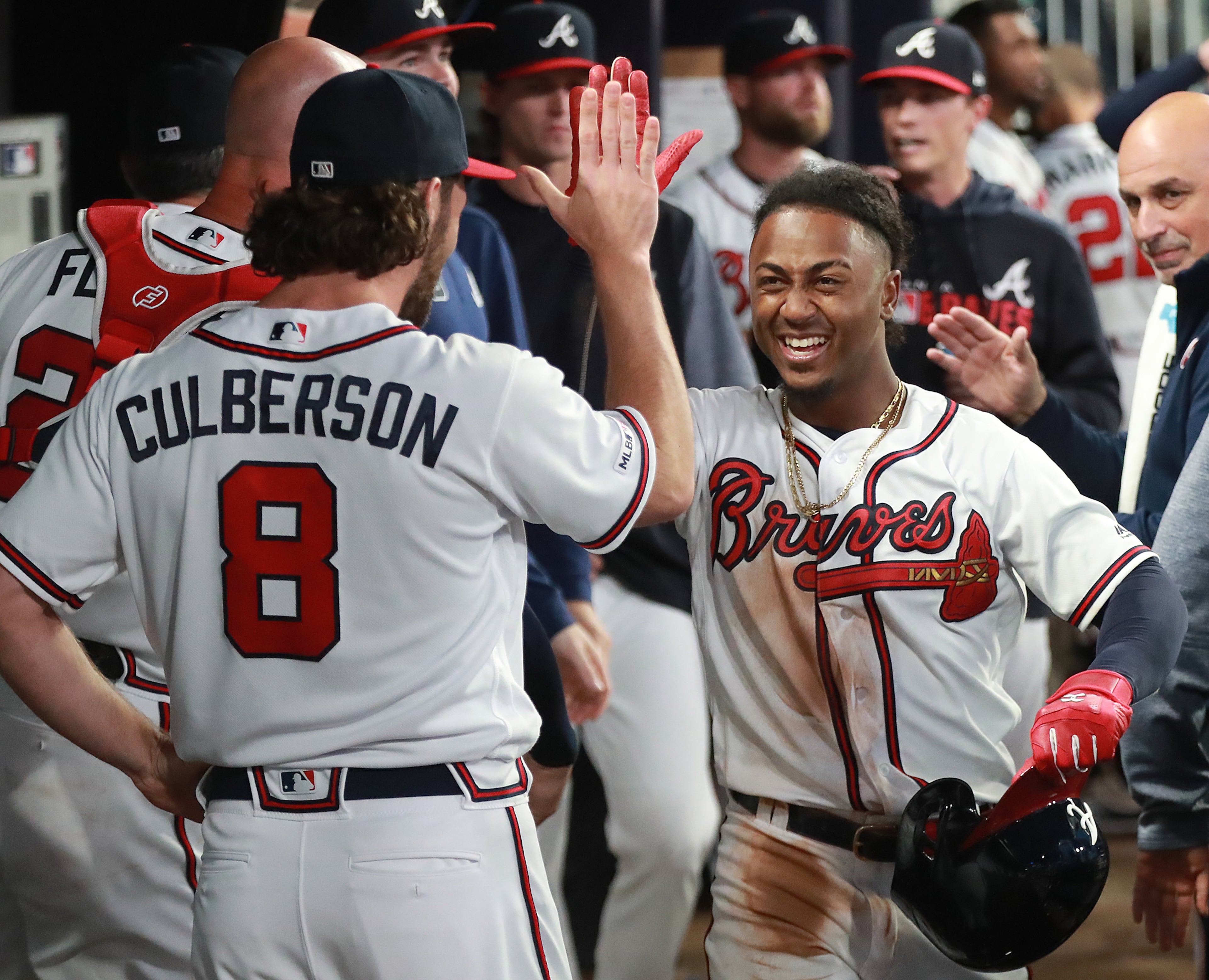 Ozzie Albies gets five from Charlie Culberson in the dugout after hitting a solo home run. Curtis Compton/ccompton@ajc.com
