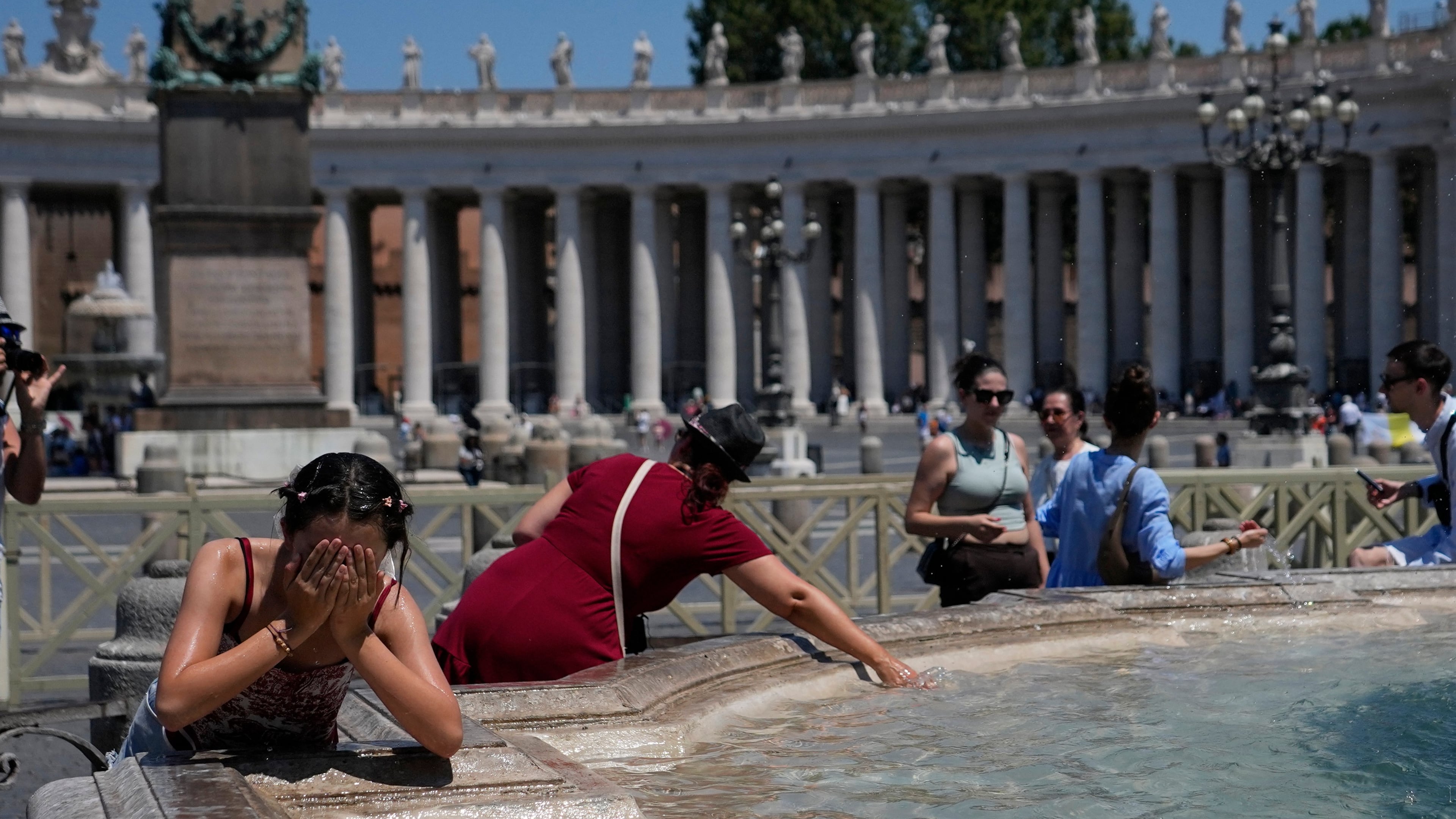People refresh in a fountain after the Angelus noon prayer celebrated by Pope Leo XIV from the window of his studio overlooking St.Peter's Square, at the Vatican, Sunday, June 28, 2026. (AP Photo/Alessandra Tarantino)