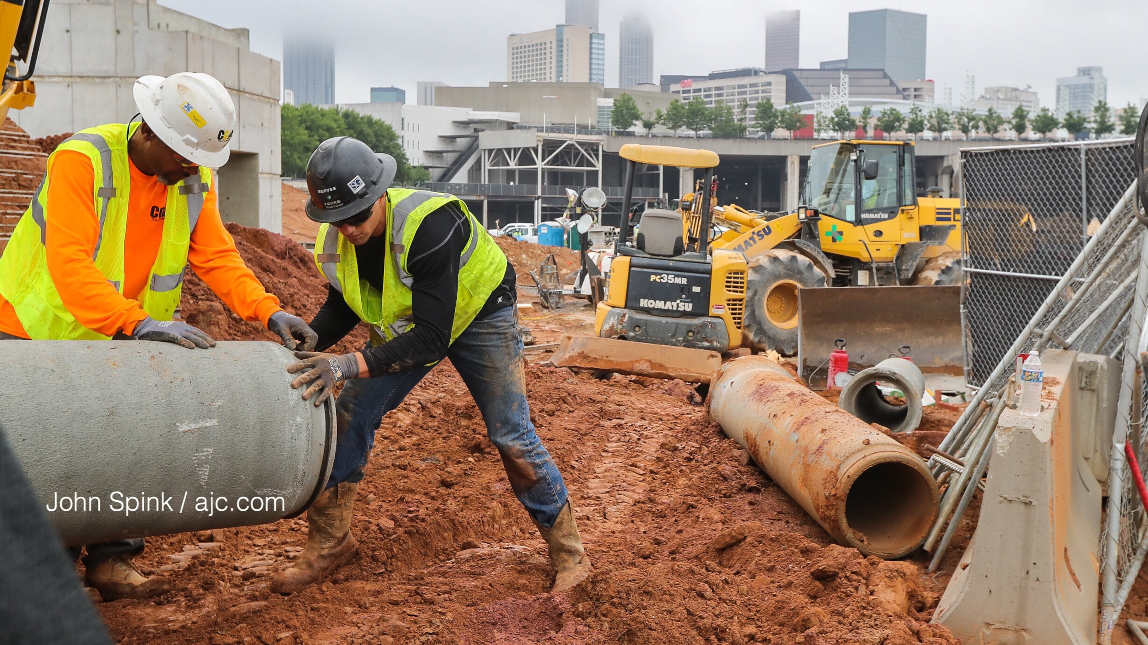 Fog covers Atlanta as Reeves and Young Construction workers Joseph Jackson, left, and Tom Palmer put piping into place at the Home Depot Backyard next to Mercedes Benz Stadium.