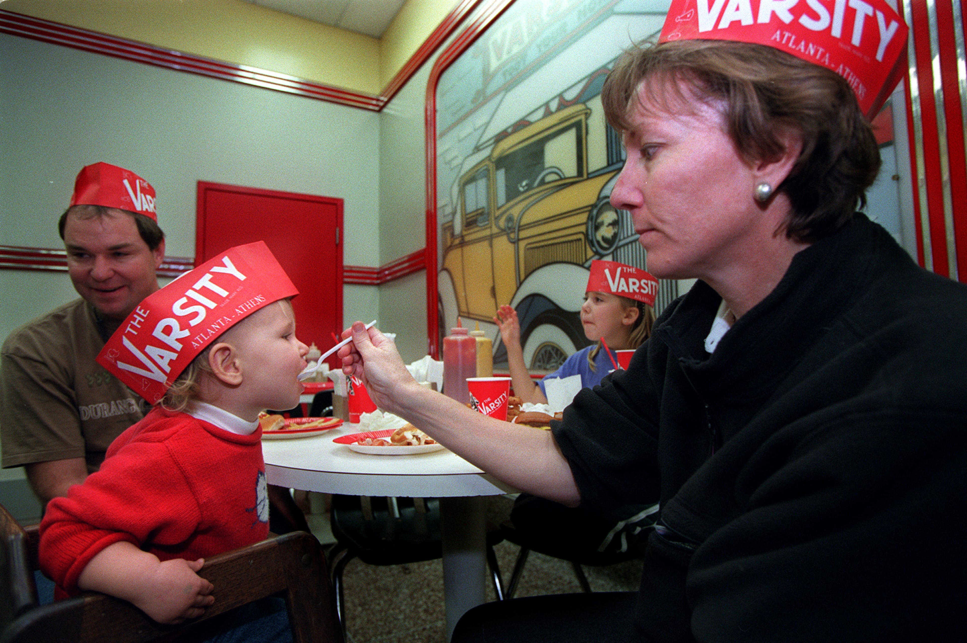 981126 ATLANTA, GA -- Lana Winings (cq) feeds her 20 month old son, Taylor Winings (cq), a spoon full of 'frosted orange' at the Varsity in Downtown Atlanta. Her family had come for lunch and will eat their Thanksgiving dinner later in the day. To the left is her husband, David Winings (cq) and her daughter Triana (cq) is in the background. (ALICIA HANSEN/STAFF)